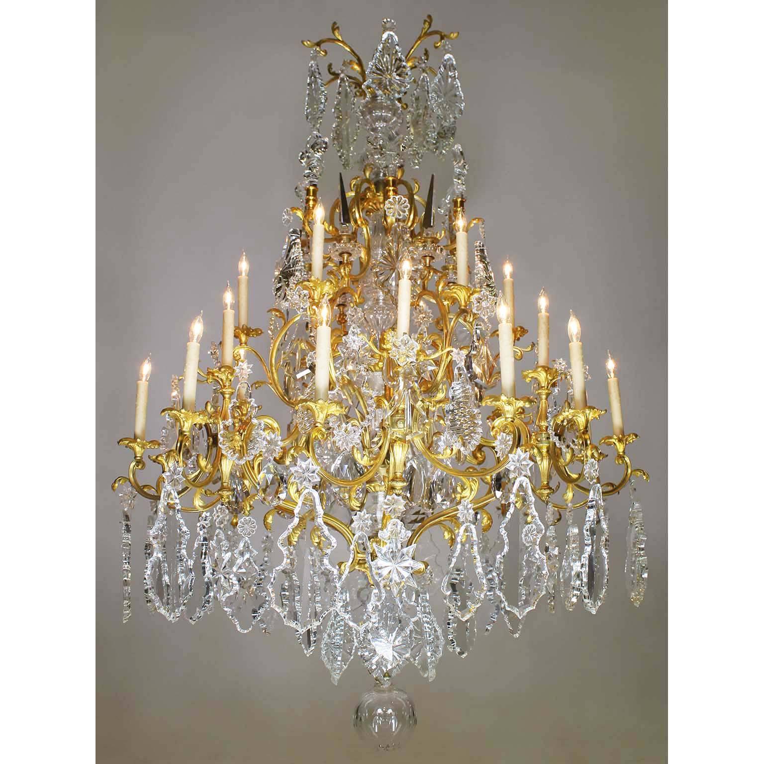 Raffinato lampadario a ventiquattro luci in stile Luigi XV del XIX secolo, in bronzo dorato, cristallo e vetro tagliato, probabilmente di Baccarat. Lo stelo centrale in vetro tagliato modellato è sormontato da obelischi di cristallo, fleur de lis e