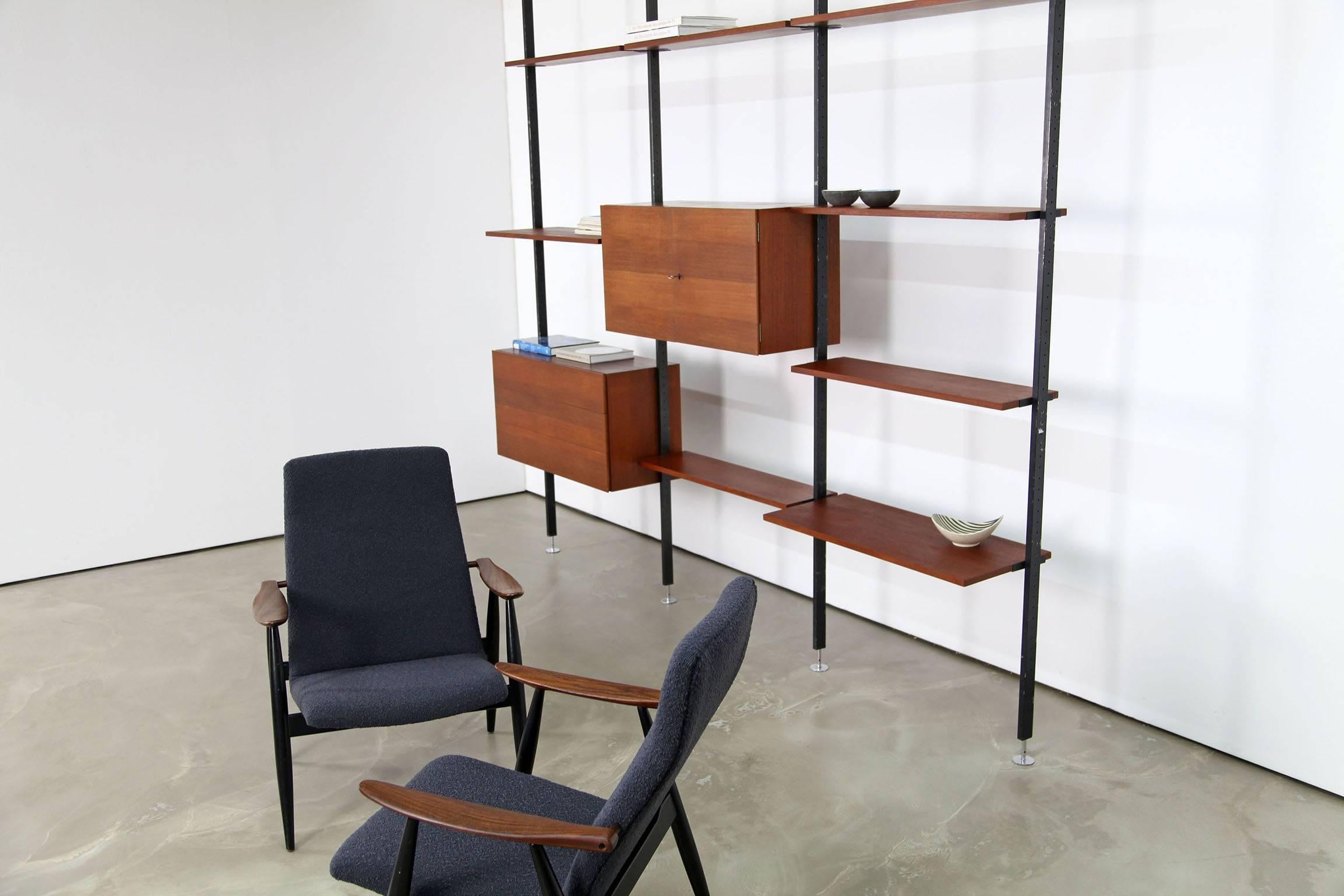 Freestanding wall-unit designed by Ulrich P. Wieser for Bofinger - Wohnbedarf AG, Switzerland in 1958. It comes with two teak veneered compartments and boards. The four black painted steel profiles are height adjustable and are fixed between floor