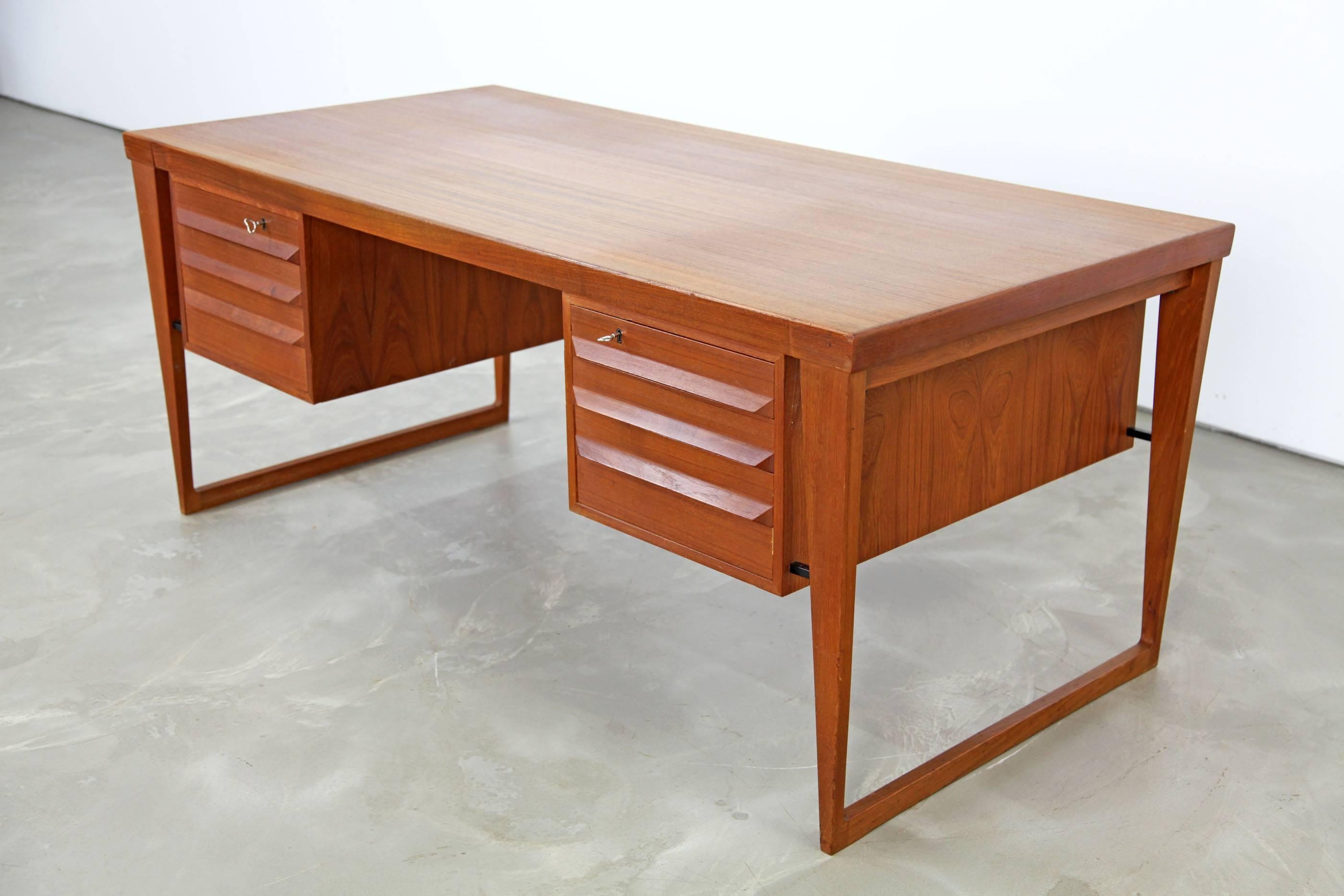 Beautiful teak executive desk designed by Kai Kristiansen. The desk features a stunning design, with sledge feet and additional compartments on the back. Original keys included.