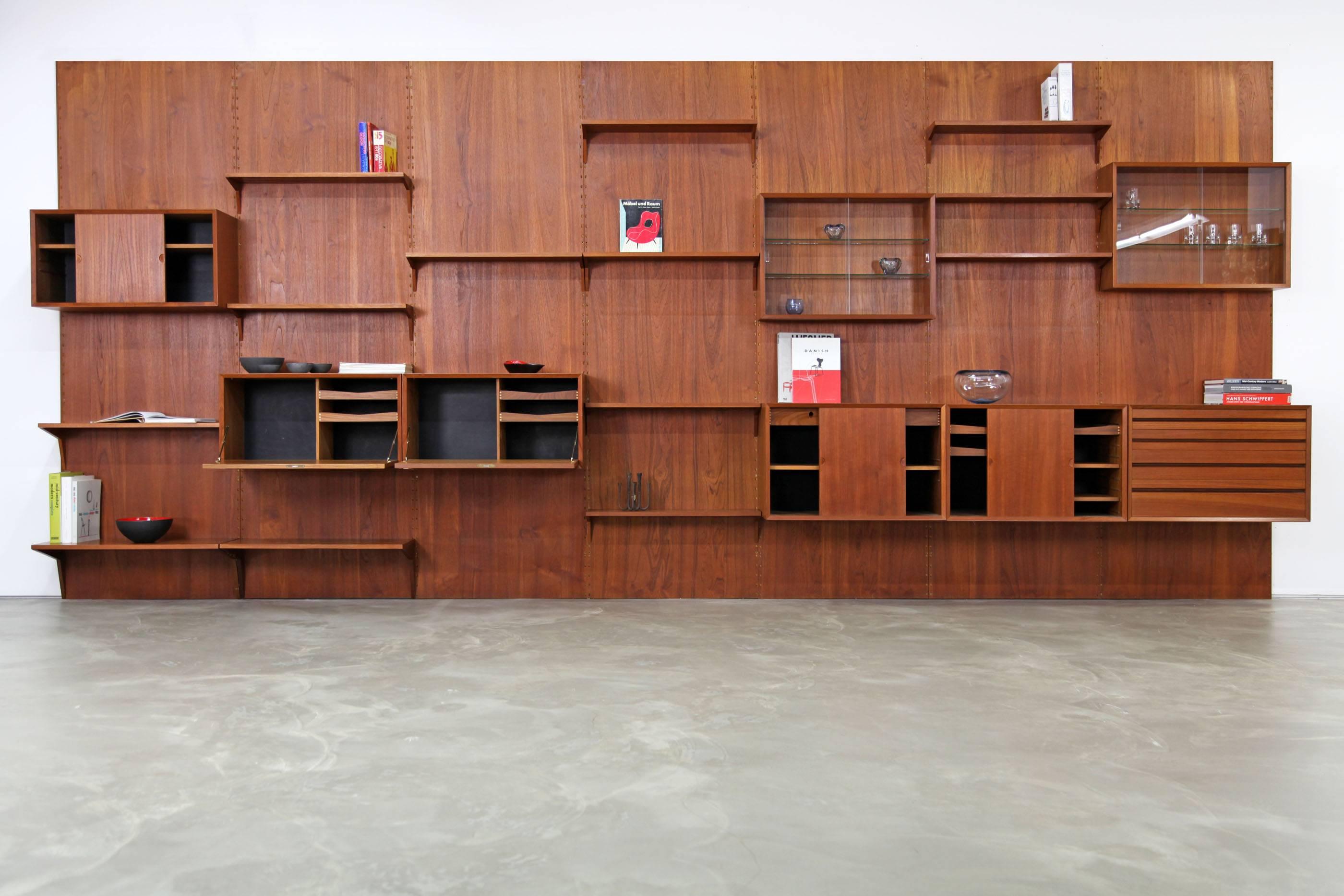 Danish modern shelving system by Poul Cadovius in teak. The wall unit and its individual elements are fully modular. The system includes, seven panels, eight different cabinets and twelve boards. It is in excellent condition.
    