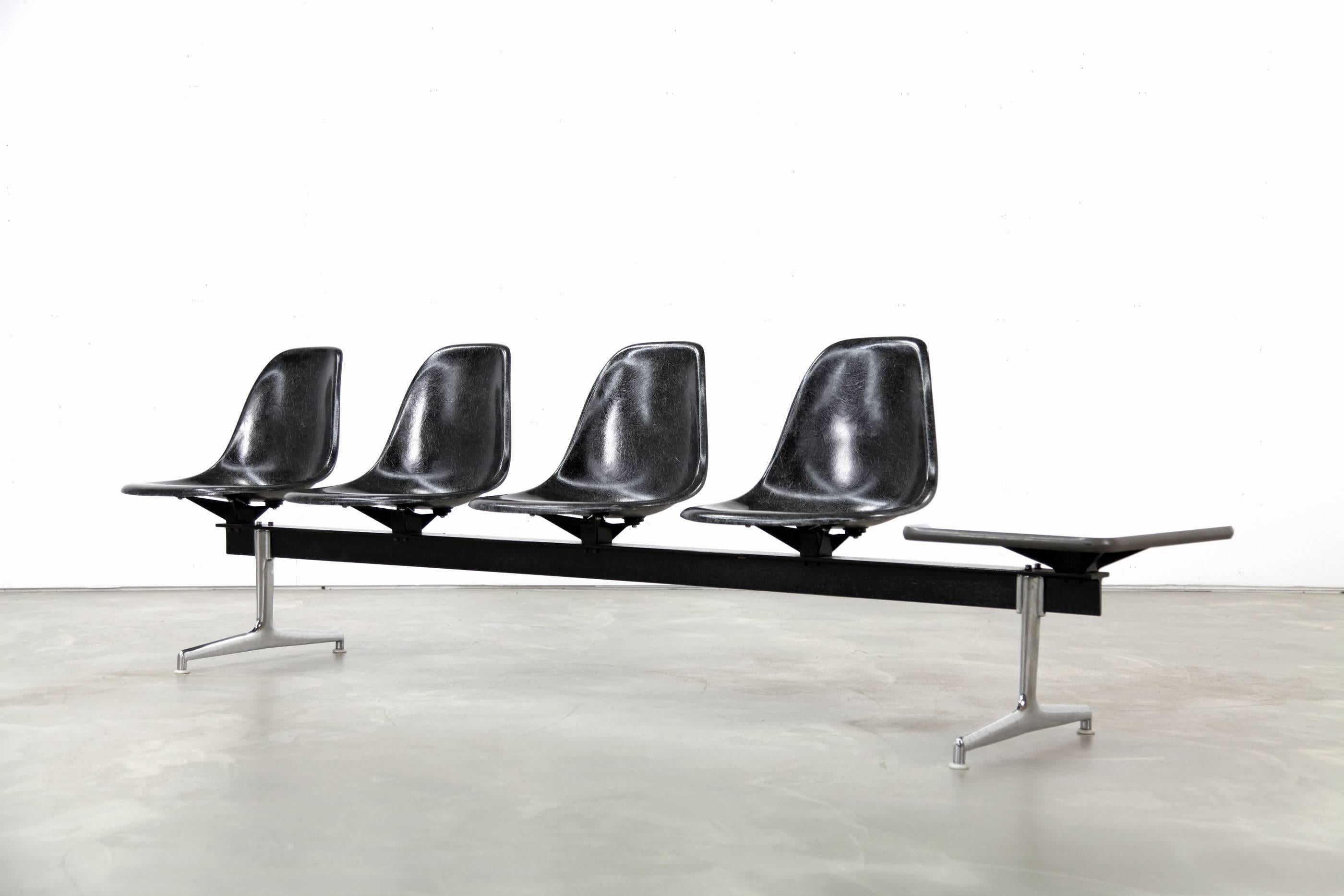 Rare tandem shell seating designed by Charles & Ray Eames, USA in the 1950s. This piece features four black fiberglass seats and formica table on a chromed and black metal base.
