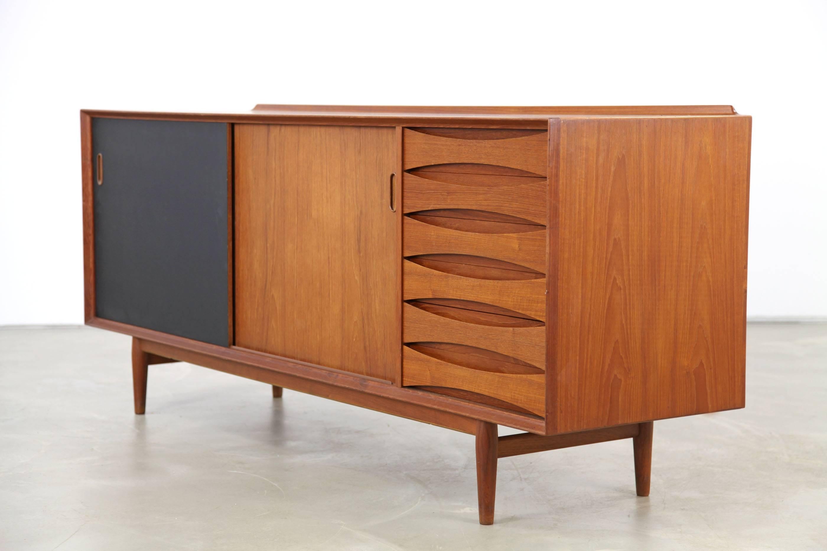 This iconic sideboard by Arne Vodder features a beautiful teak veneer and reversible doors, that are matte black on one side and teak veneered on the other. It can be used as a room divider.