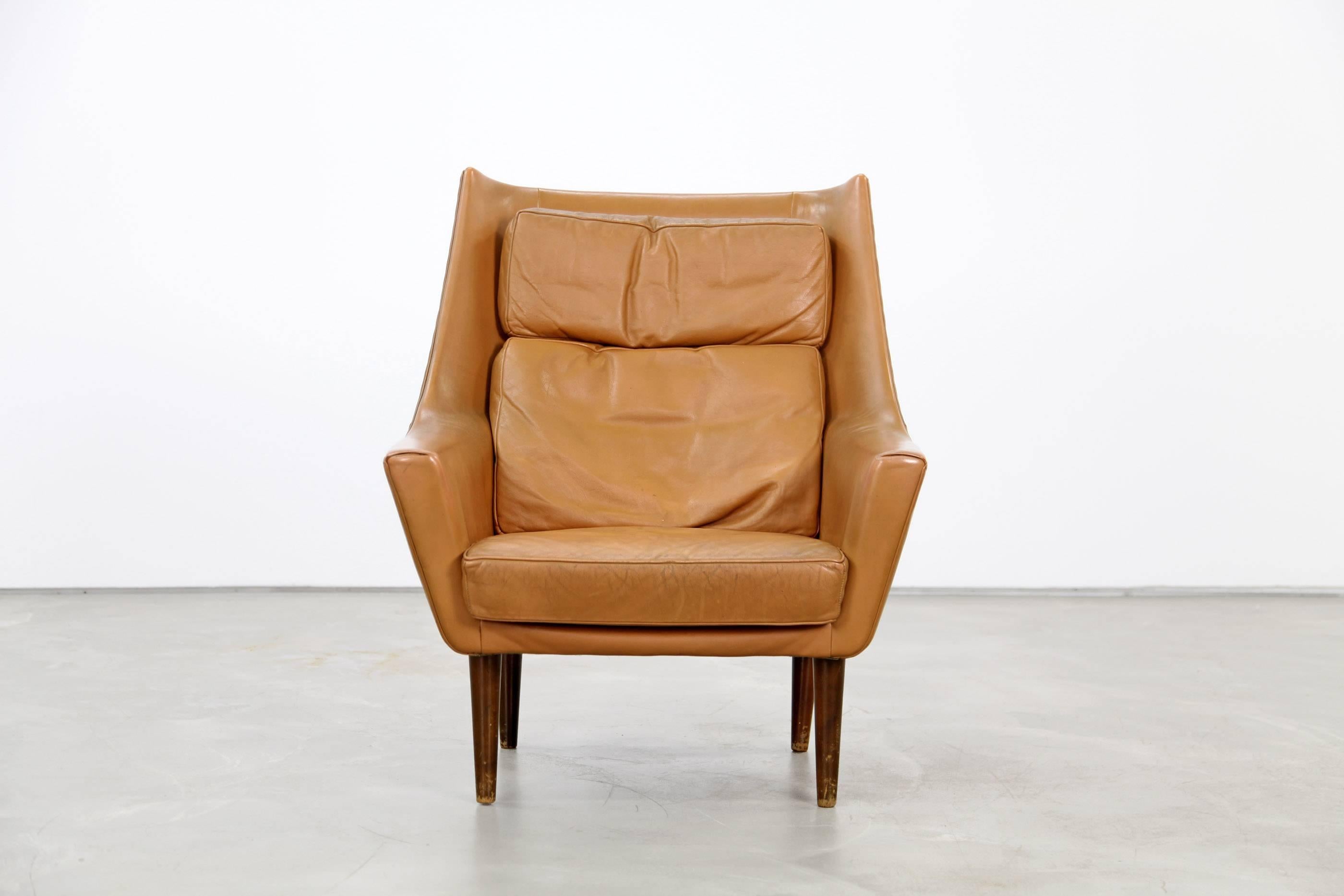 Beautiful leather lounge chair from the 1960s. This chair was produced in Denmark, the design is attributed to Hans Olsen. The chair is upholstered in cognac-colored original leather and is in beautifully patinated condition. We have two matching