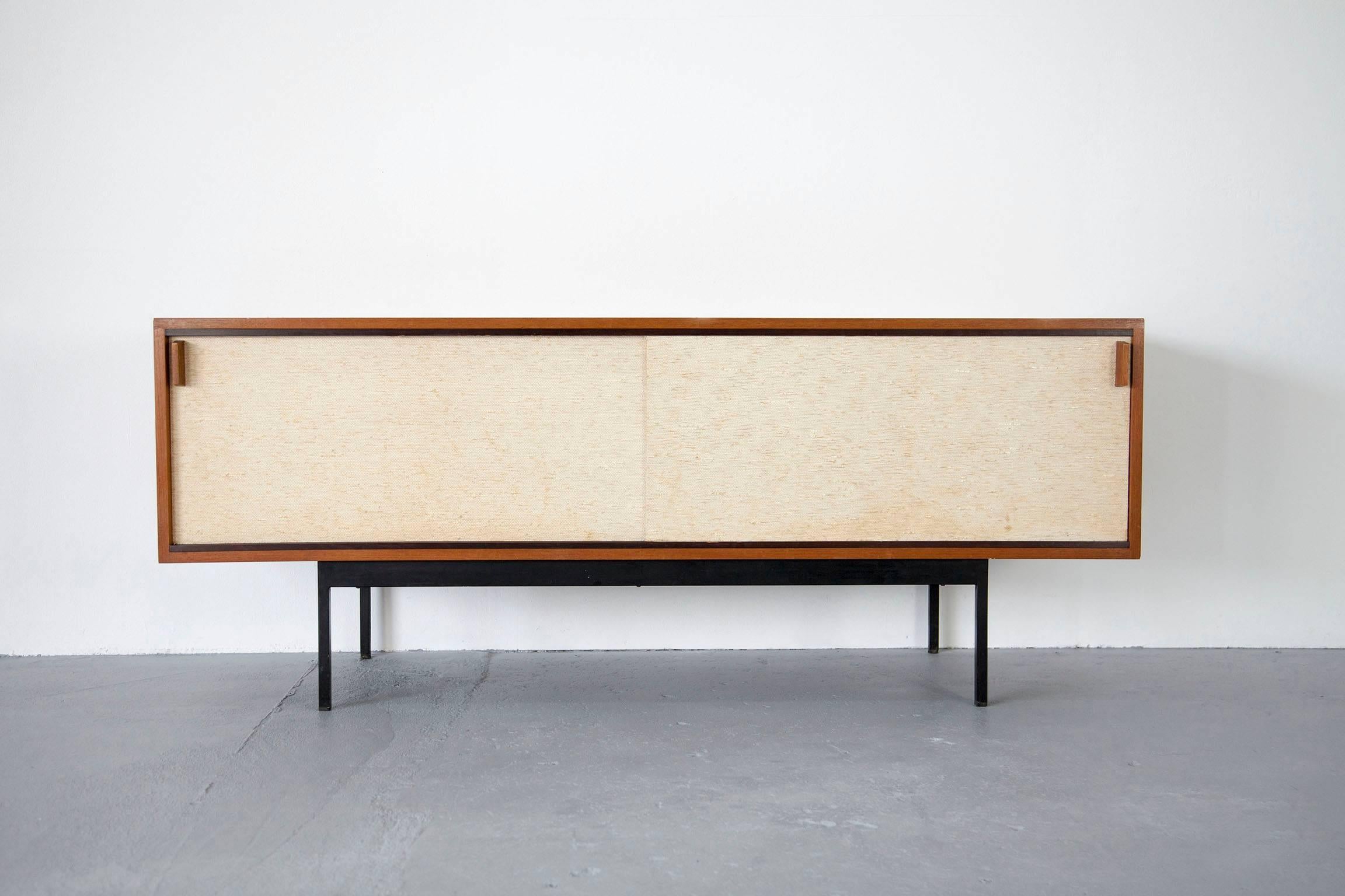 A rare piece of furniture from the early 1960s. The sideboard is veneered with teak on the outside and maplewood on the inside. The sliding doors are covered with seagrass.