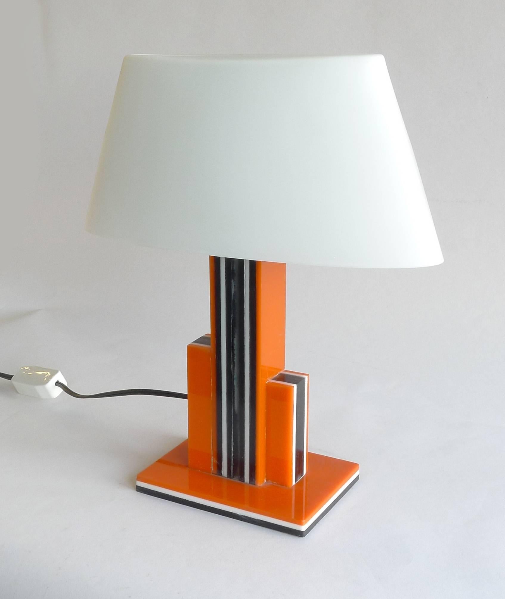 Art Deco black, orange and clear Lucite layers. Assumed to be made sometime in the 1940s. Cord plug and switch, wired for incandescent. A second one is available. White glass shade is new.

Architect, Sandy Littman of Duesenberg LTD.  and The