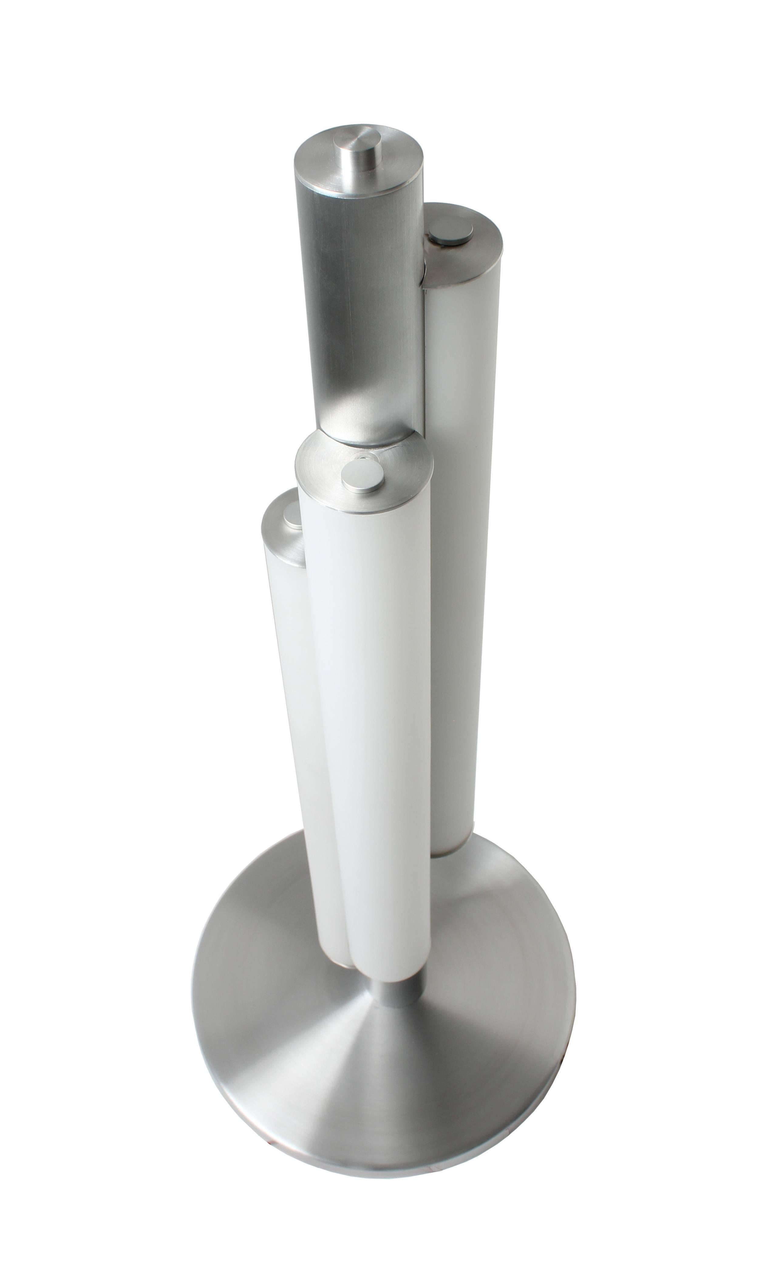 In the manner of Art Deco triple white glass cylinder table lamp. Aluminum center tube supports three glass cylinders with rhythmic height differences. LED 3000K standard color temperature.