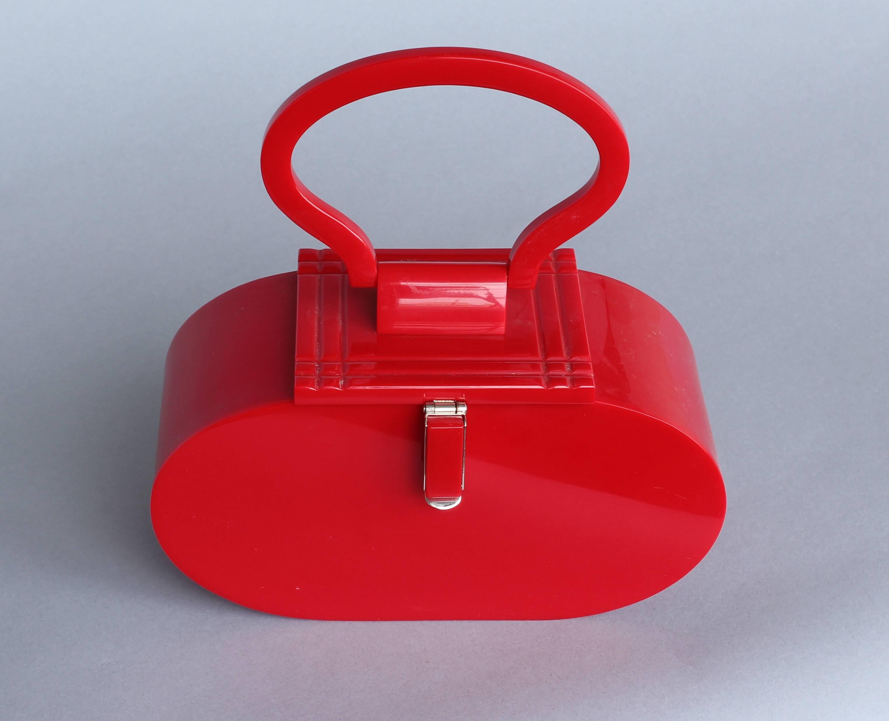 Vintage French red Lucite handbag with chrome clasp. Purchased in Paris, mid-1960s. Hinged top with beveled groove pattern. Excellent condition.

Architect, Sandy Littman of Duesenberg LTD.  and The American Glass Light Company have been making