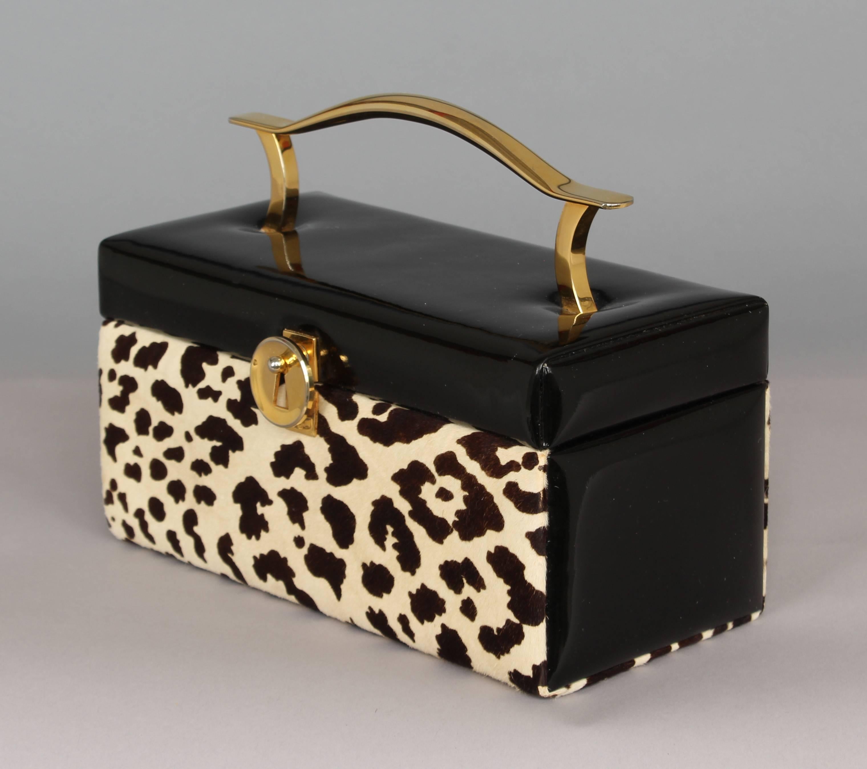 Kored Box shaped handbag in faux leopard and black patent leather, sculptural brass handle, clasp and hinge details. Original purse and mirror included.

Architect, Sandy Littman of Duesenberg LTD.  and The American Glass Light Company have been