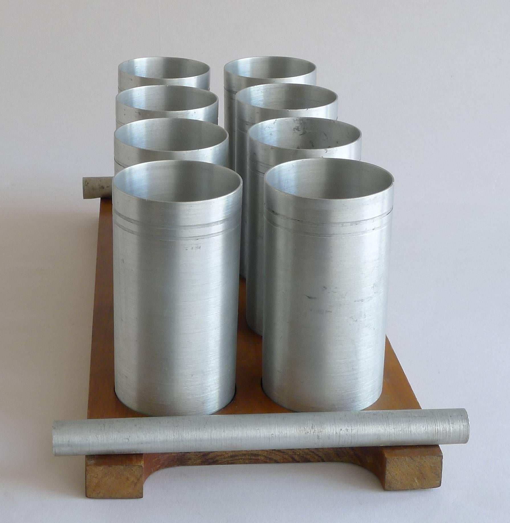 1940s Art Deco wood and satin aluminium cup set. Set includes eight cups, each with incised double line just below the lip. Wood tray has two satin aluminium tube handles. Bottom of tray has a 