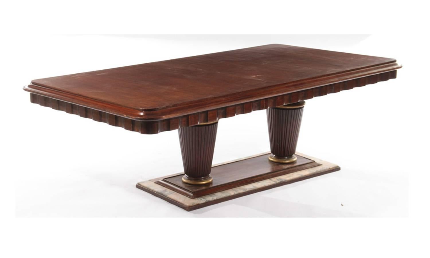 A mahogany and marble Art Deco dining room table, circa 1935. Continuous fluted top, with two large columns and marble as base. Has a storage drawer on one side. Could use some touchup and refinishing, this is reflected in the price. Sale includes