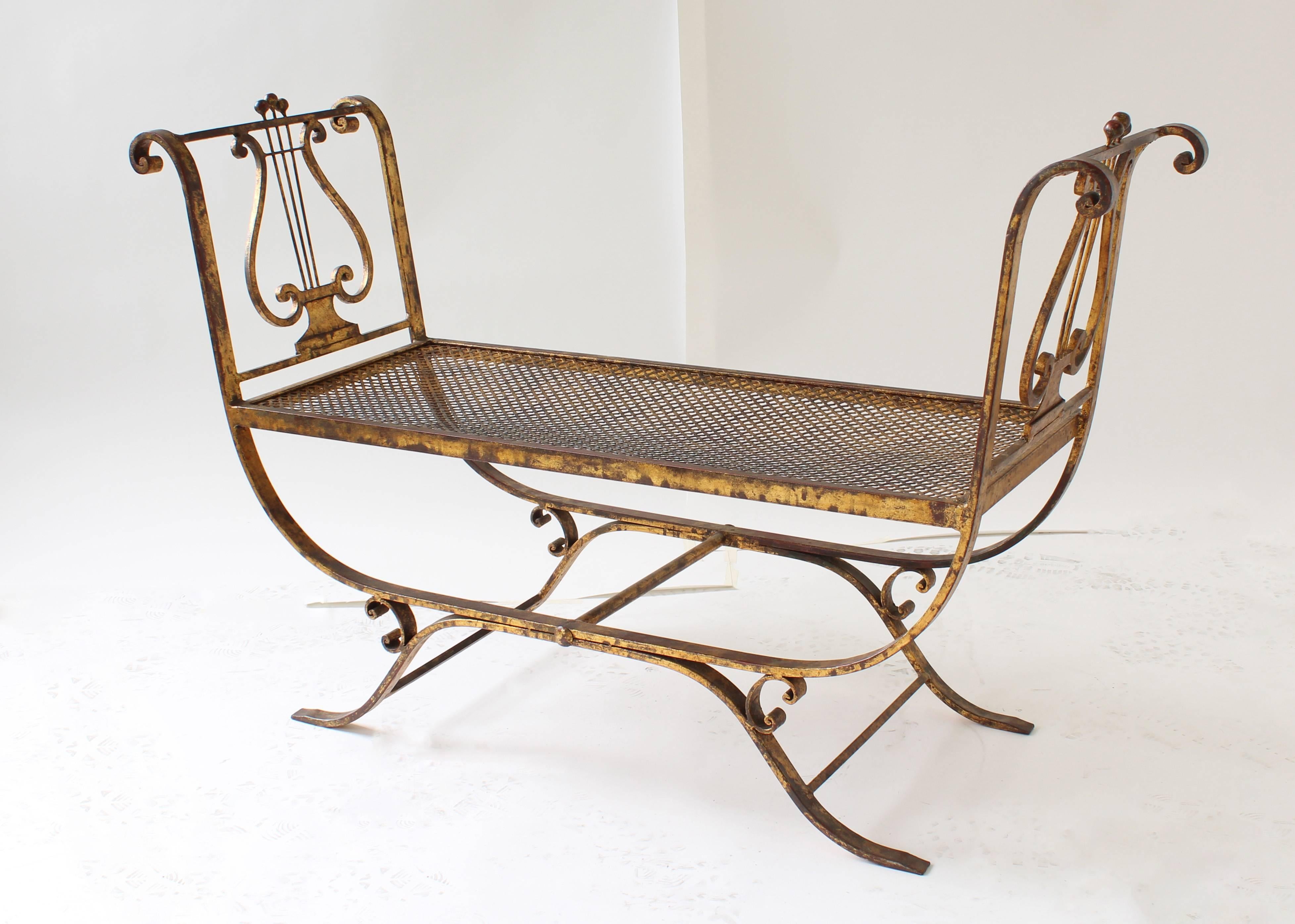 Wrought iron painted and gilt chandelier with fifteen arms. Crystal pentalogs and floral details. From the Hollywood Regency period. Gold fabric ruffled chain cover included. Incandescent lamping. Included in purchase is gilt metal lyre form bench.