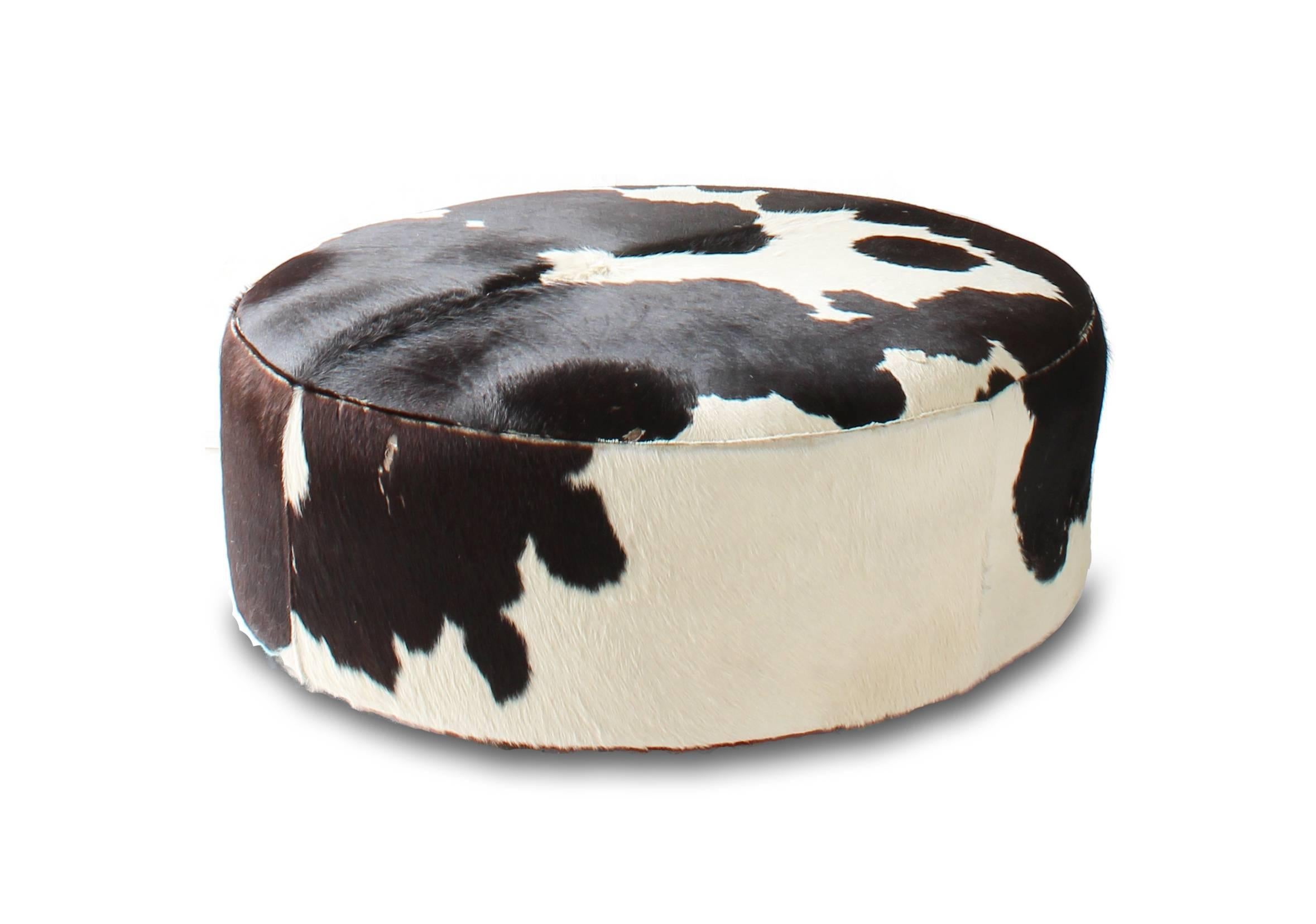 Black and white pony hide round ottoman with recessed feet, circa 1960. Ottoman shows some signs of wear. Purchase includes Mid-Century Modern inspired Avocado chandelier in satin aluminium with white glass shades. Chandelier dimensions 58 inches x