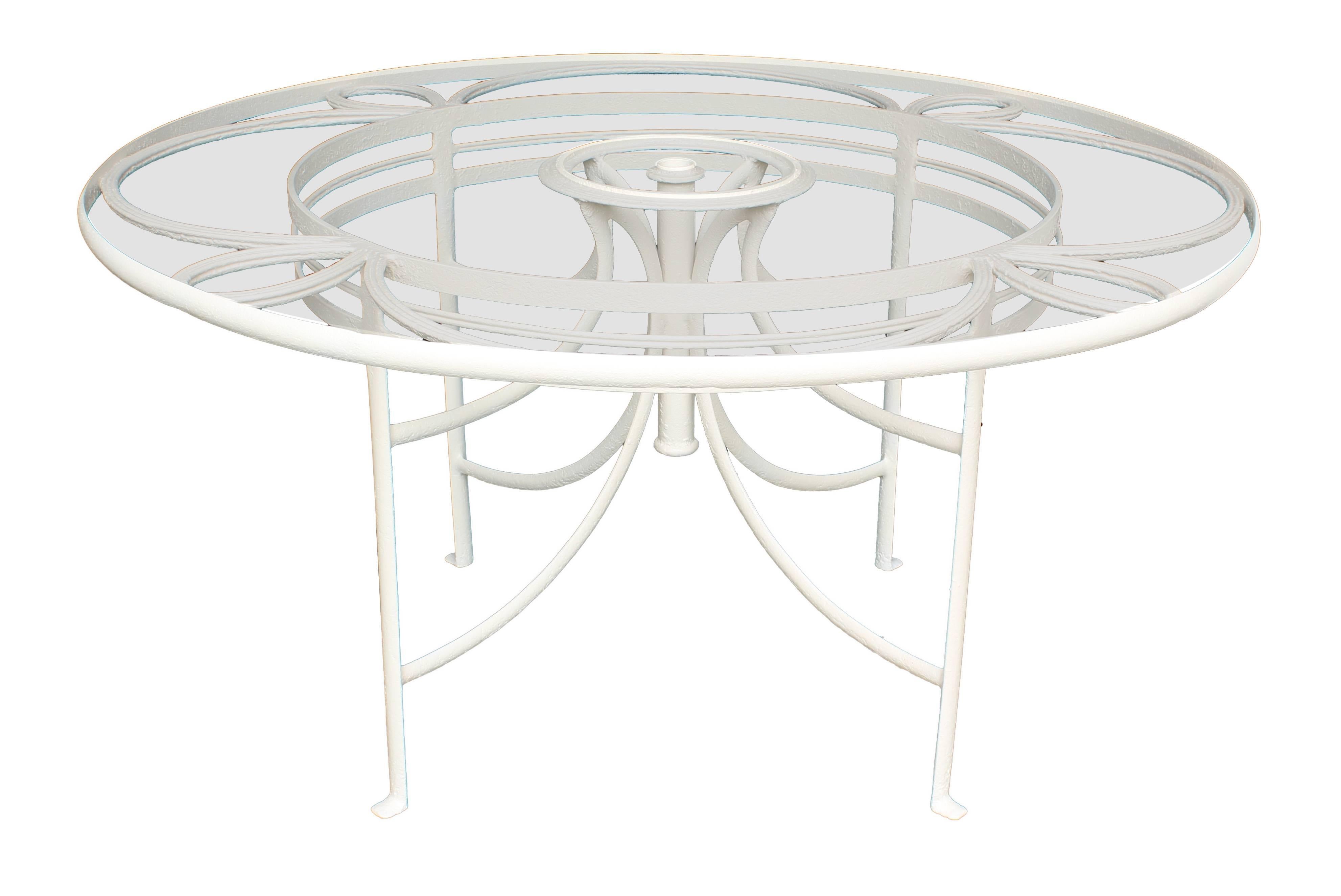 1930s French iron and glass 57 inch diameter round table for outdoor or sun room. Center tube for use with umbrella. Has been refinished with off-white outdoor paint. Purchase includes a set of 12 French wrought iron garden chairs attributed to Rene