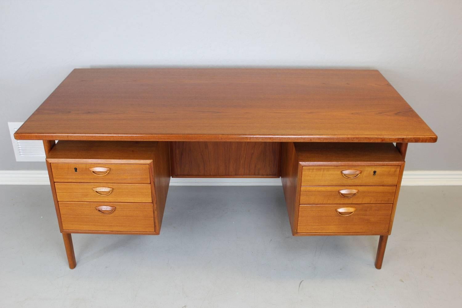 Floating teak desk by Kai Kristiansen, circa late 1950s. On the back side of this desk there is one open compartment and also two cabinet doors that contain storage compartments. Note the floating teak top and six drawers with teak handles. This