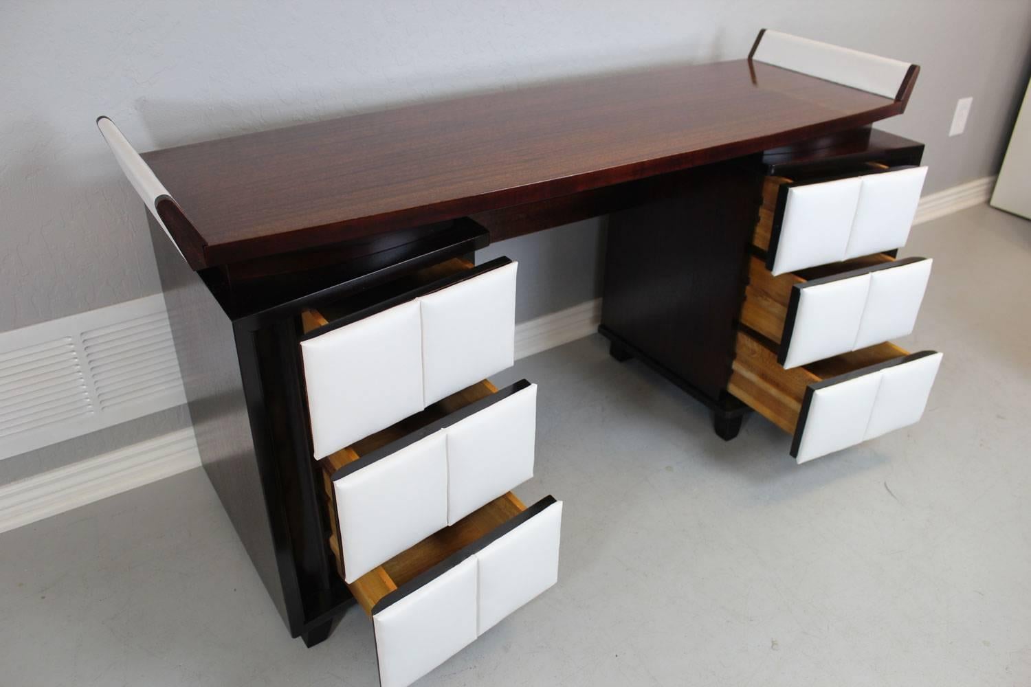 A sculptural vanity by Gilbert Rohde for Herman Miller. Floating top.  Base cabinets contain three drawers on each side with padded leatherette covered drawers. Professionally restored. 

