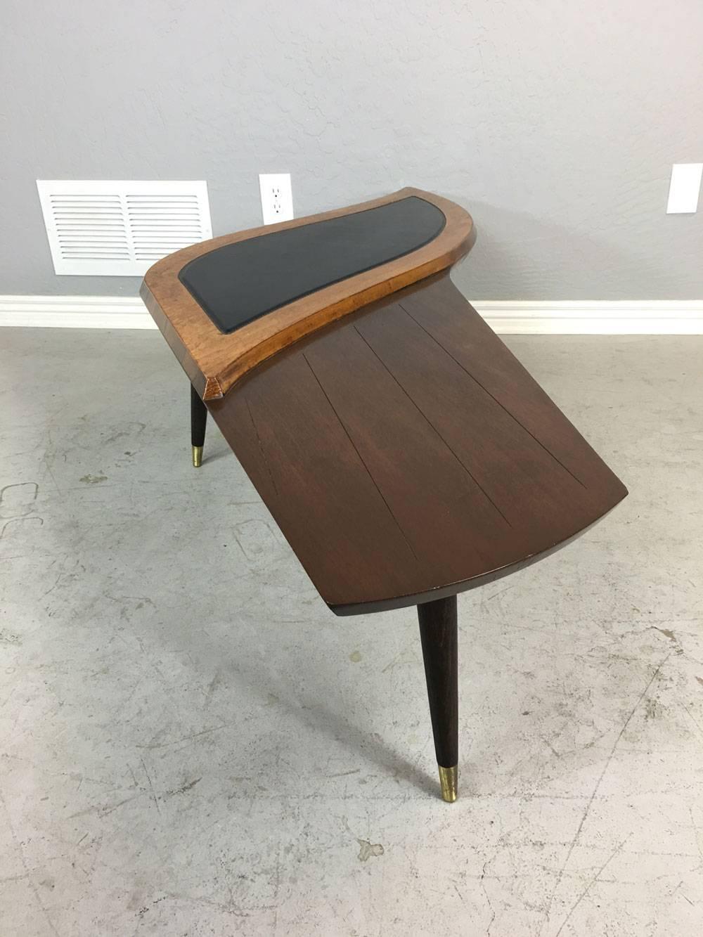 Unique two-toned, three legged Mid-Century Modern coffee table by Paisley. Leather on raised top portion. Stained walnut on the balance of this piece. Flared pencil legs with brass tips. Stunningly different. 

Dimensions: 61