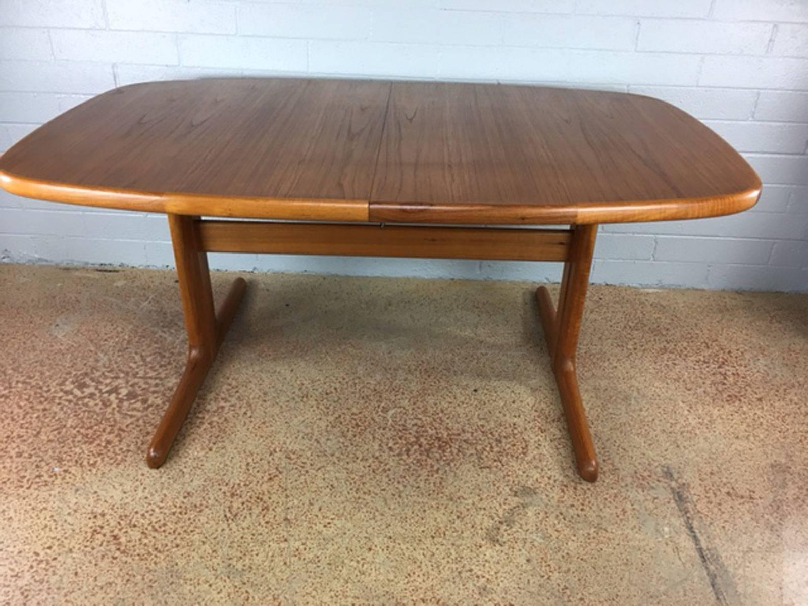 Teak dining table with two undermount leaves by Dyrlund. Leaves are each 15 inches wide adding 30 inches to the table width, circa 1960s.  A picture with the two perfectly matching leaves is included. 

Dimensions:  65 inches W (without leaves) x