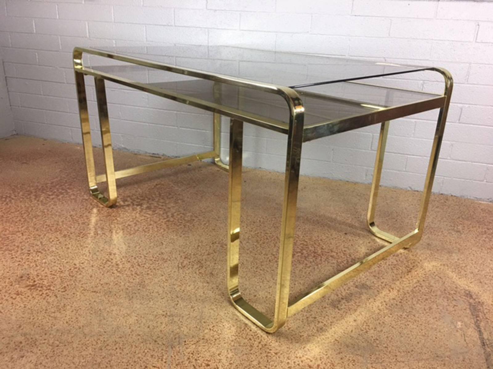 Brass metal finish desk designed by Pierre Cardin for Design Institute of America (DIA). Two levels of smoked inset glass. All glass supports are present. Manufactured in 1983. 

Desk opening area for seating measures 35