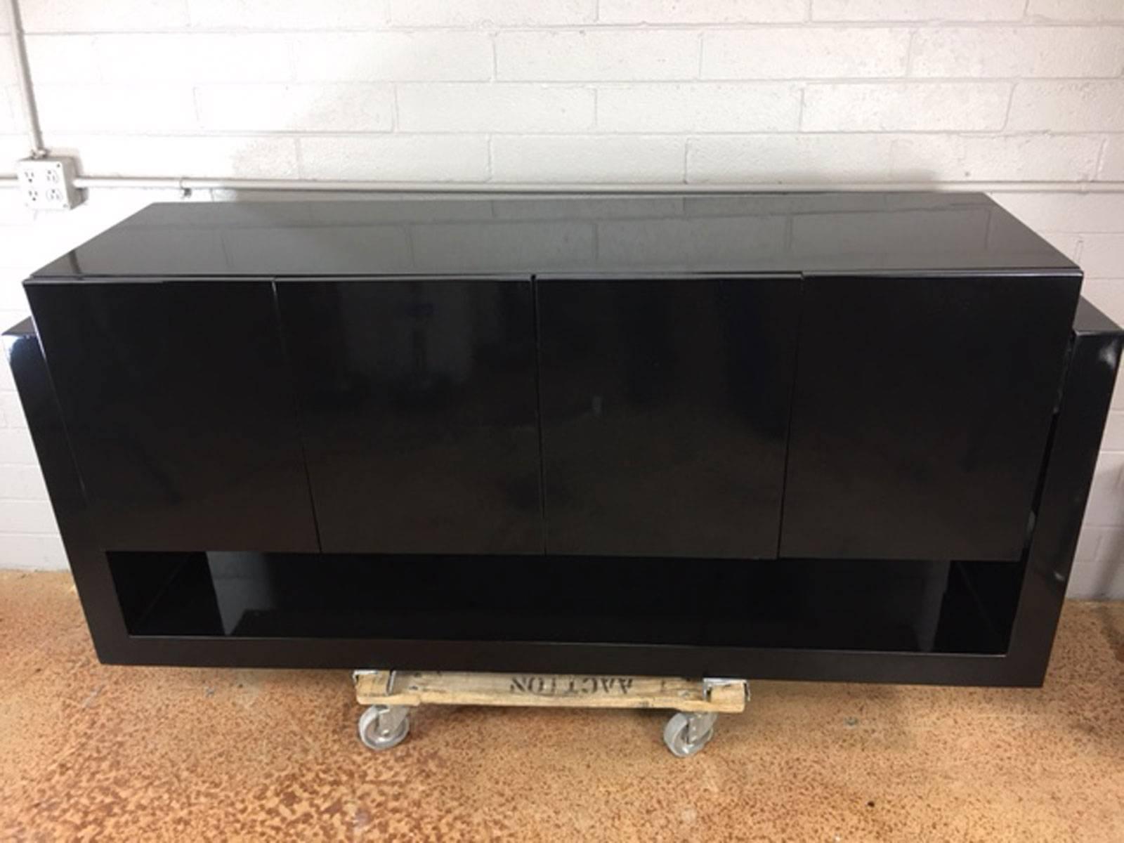 Floating illuminated credenza suspended with Lucite joints on a high gloss black lacquered support base. This credenza is illuminated from underneath the cabinets with two different lights which provides a very warm glow.