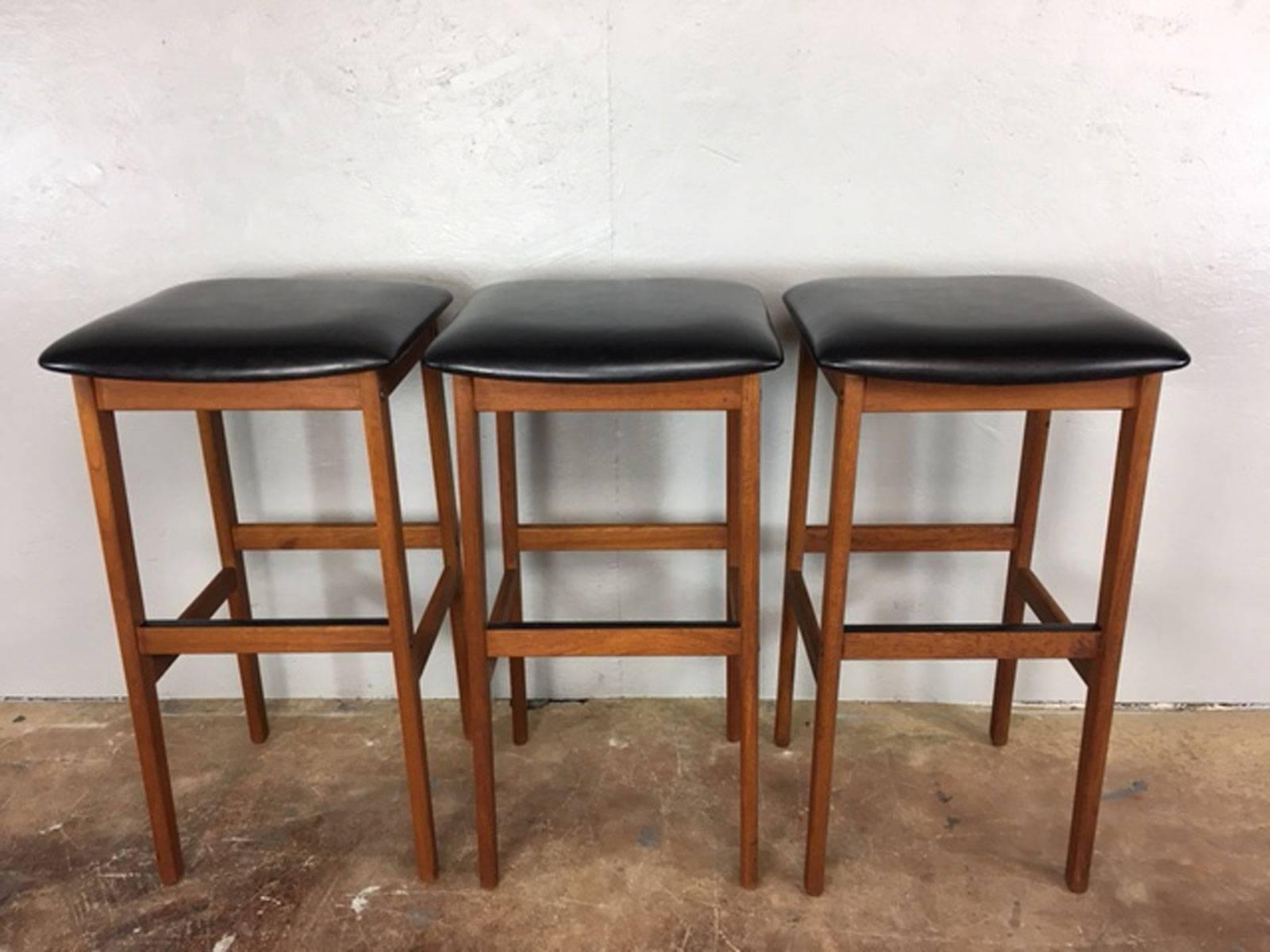 Nice set of three Danish bar stools in walnut and black leather. Marked "K.S.". Leather is in very good condition overall. As depicted, there is one small quarter inch square mar in the leather on one stool. The mar does not go through the