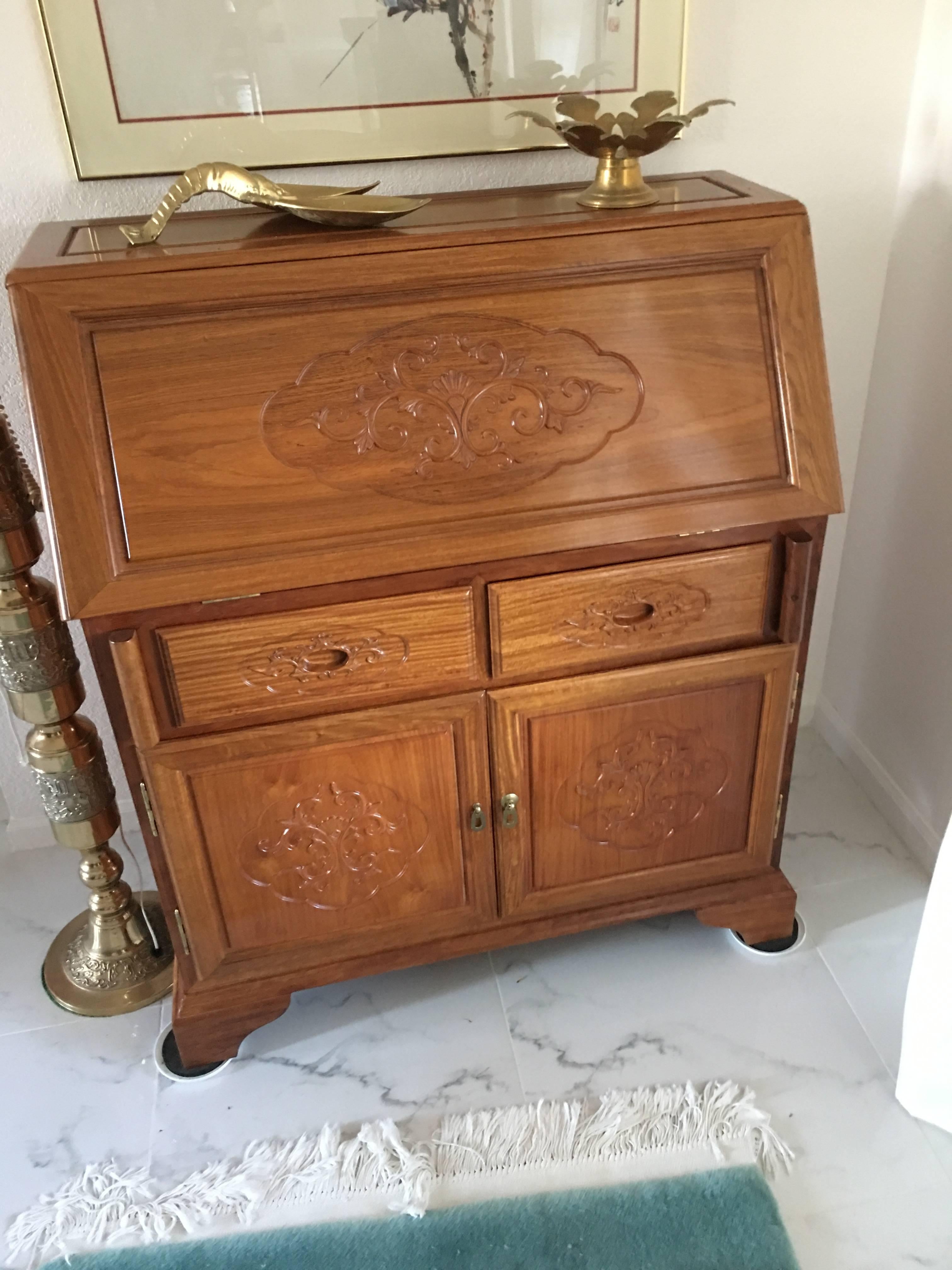 Rosewood writing desk with drop down front. 100% rosewood. No veneer in this piece, circa 1980. From Malaysia. Solid brass hardware. Golden dyed finish. Perfect condition. Absolutely no flaws. The drawer pulls have been carved into the drawer fronts