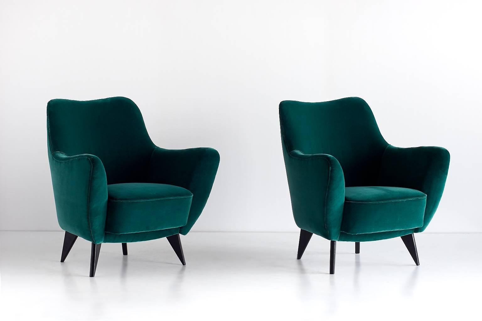 A pair of Perla armchairs designed by Giulia Veronesi and produced by ISA Bergamo, Italy. Its sensual curves and the elegantly tapered legs give the chair a sculptural and modern feel. These sumptuous armchairs have been fully reconditioned and