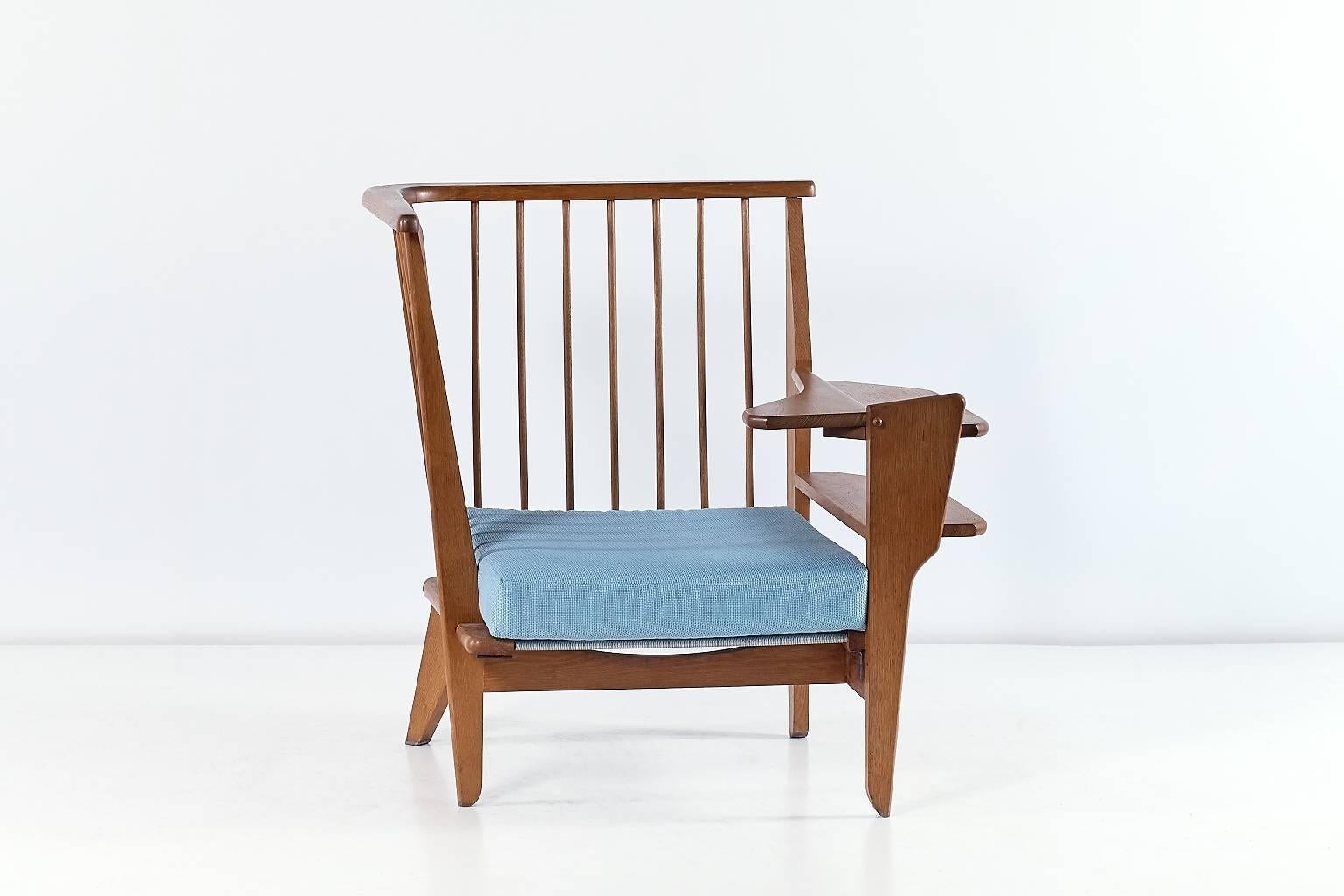 A rare and unusual corner chair in solid oak designed by Robert Guillerme and Jacques Chambron in the 1960s. This inventive chair with a single armrest offers remarkable details such as the sculpturally formed legs, the wooden slats on the side and