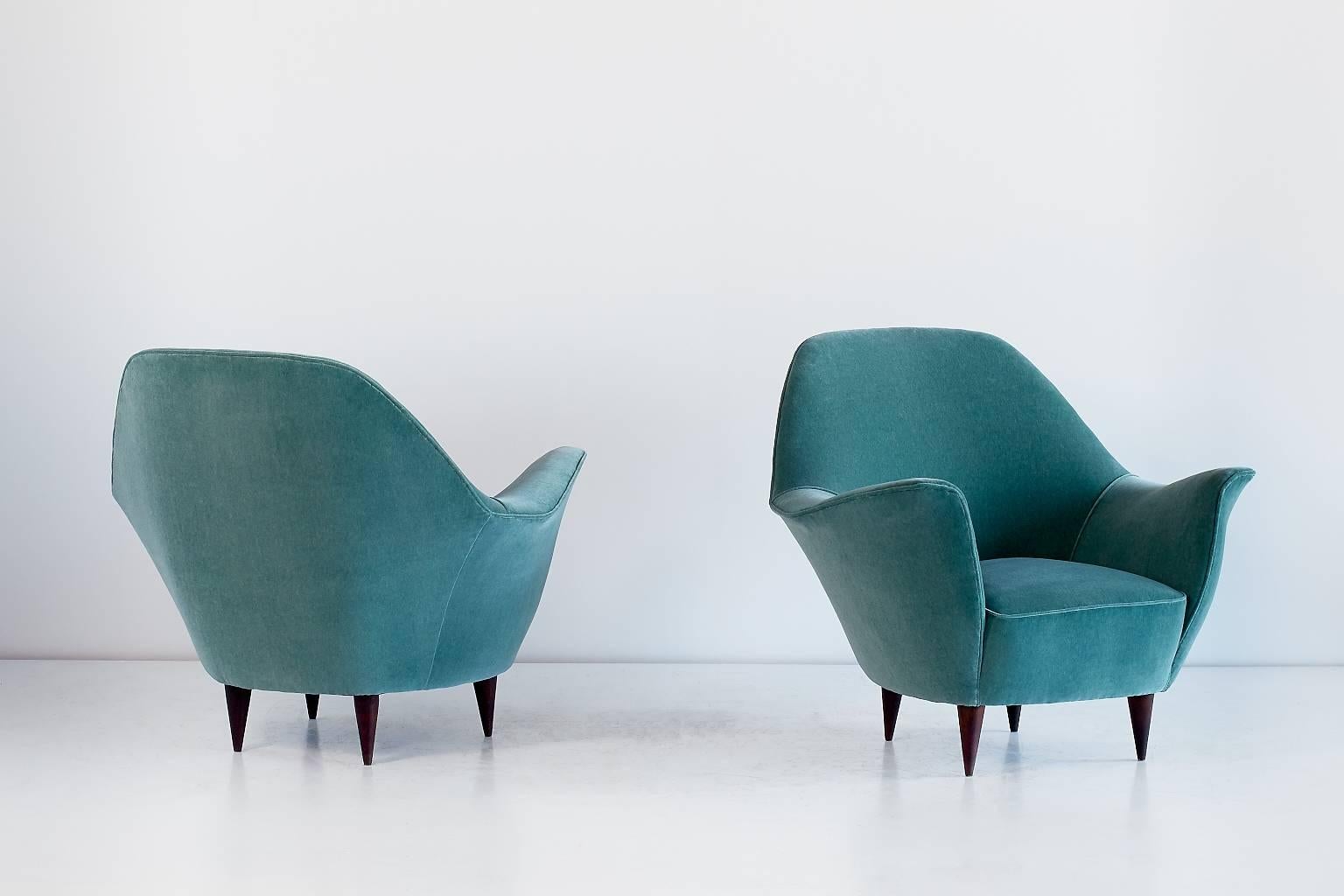 These sumptuous armchairs were designed by Ico Parisi in the early 1950s. The invitingly opened petal-shaped armrests, its striking curves and elegantly tapered legs give these chairs a sculptural and modern feel. 
The generously sized Italian