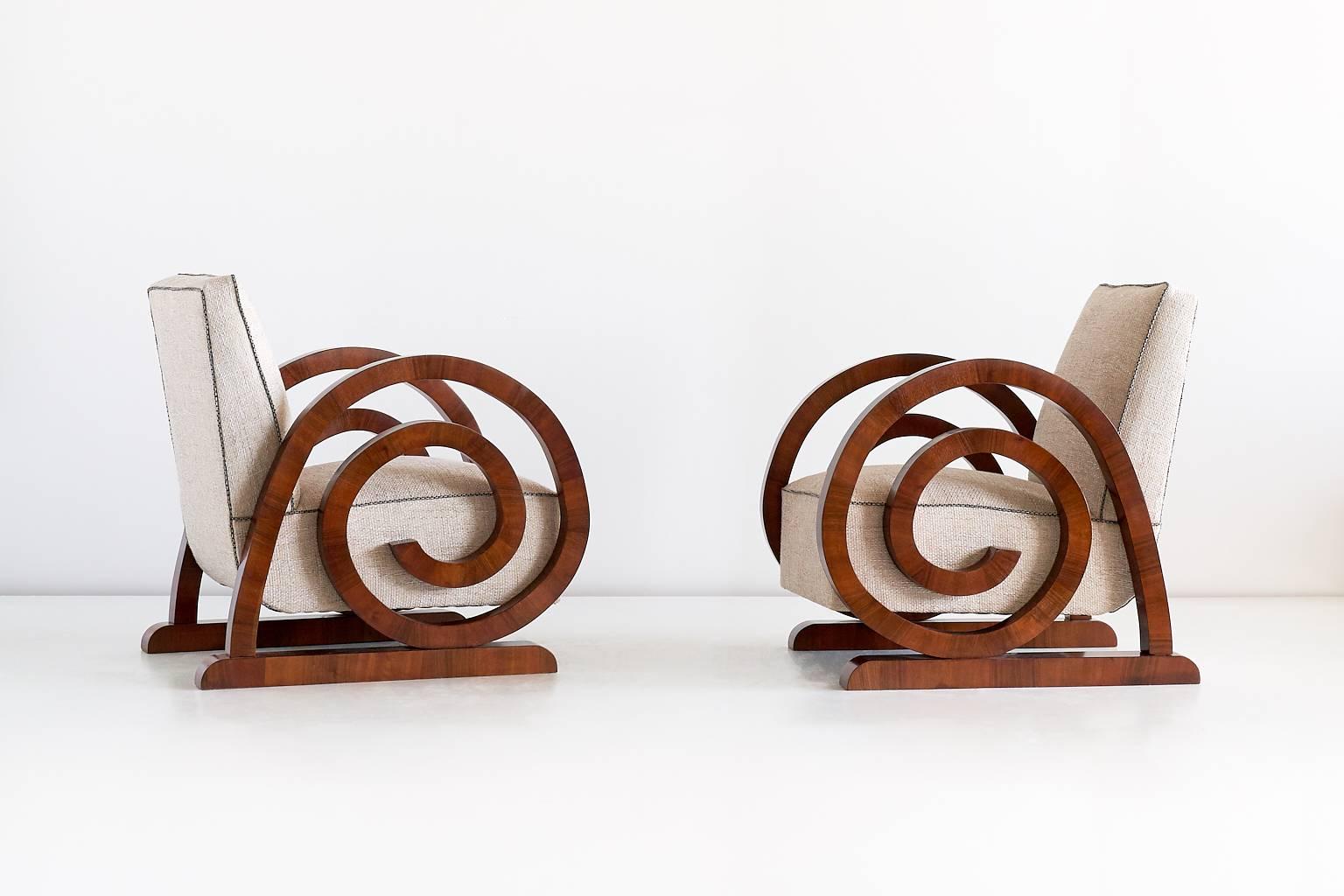 This extraordinary pair of Art Deco armchairs was produced in France in the 1930s. The dramatically curved arms are a modern interpretation of the "escargot"- or shell-motif that was prevalent in earlier French furniture periods. The