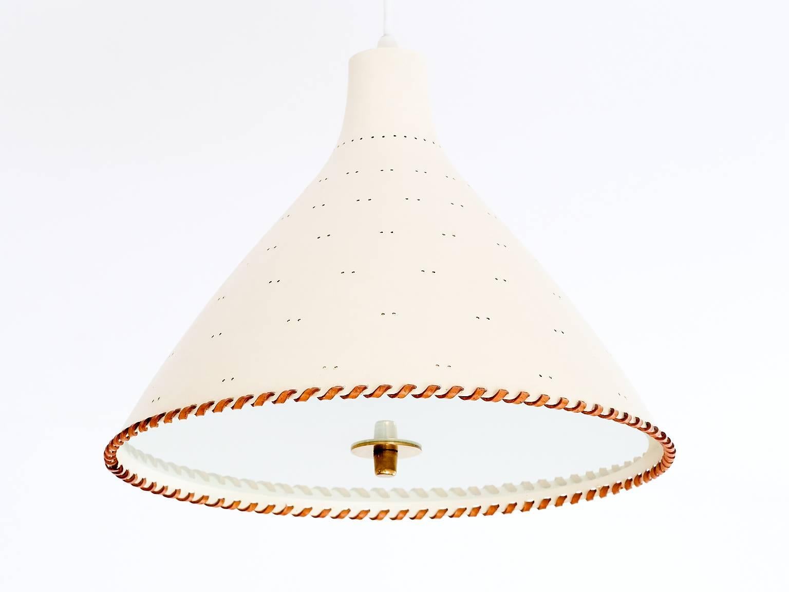 A rare pendant or ceiling lamp designed by Paavo Tynell and produced by Taito Oy in the early 1950s. The model number is J1982N and the lamp is marked with Taito. The pinhole perforations in the off-white or cream colored shade create a beautiful