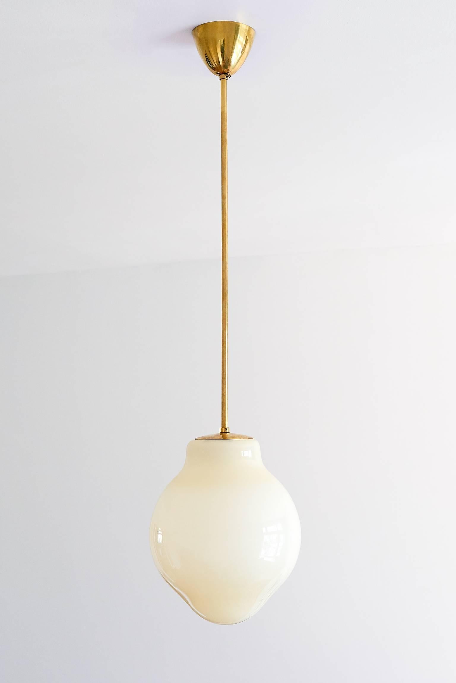This rare pendant or ceiling lamp was designed by Paavo Tynell and produced by Taito Oy in the early 1950s. The model number is 1092 and the lamp is marked with Taito. The handblown yellow glass shades provide a gentle and warm light distribution.