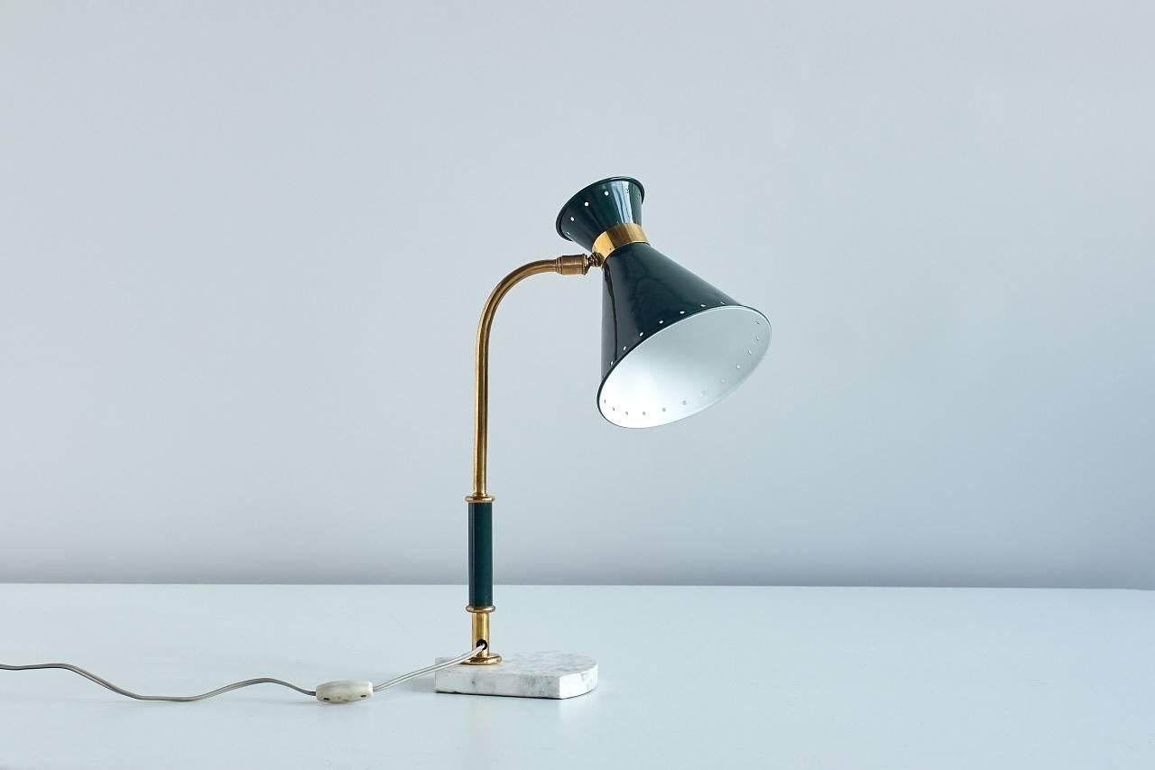 An elegant desk or table lamp, with fine details such as a white marble base, a diabolo shaped metal shade with a band of perforated holes and beautifully preserved brass parts. The shade is fully adjustable. The lamp is in excellent original
