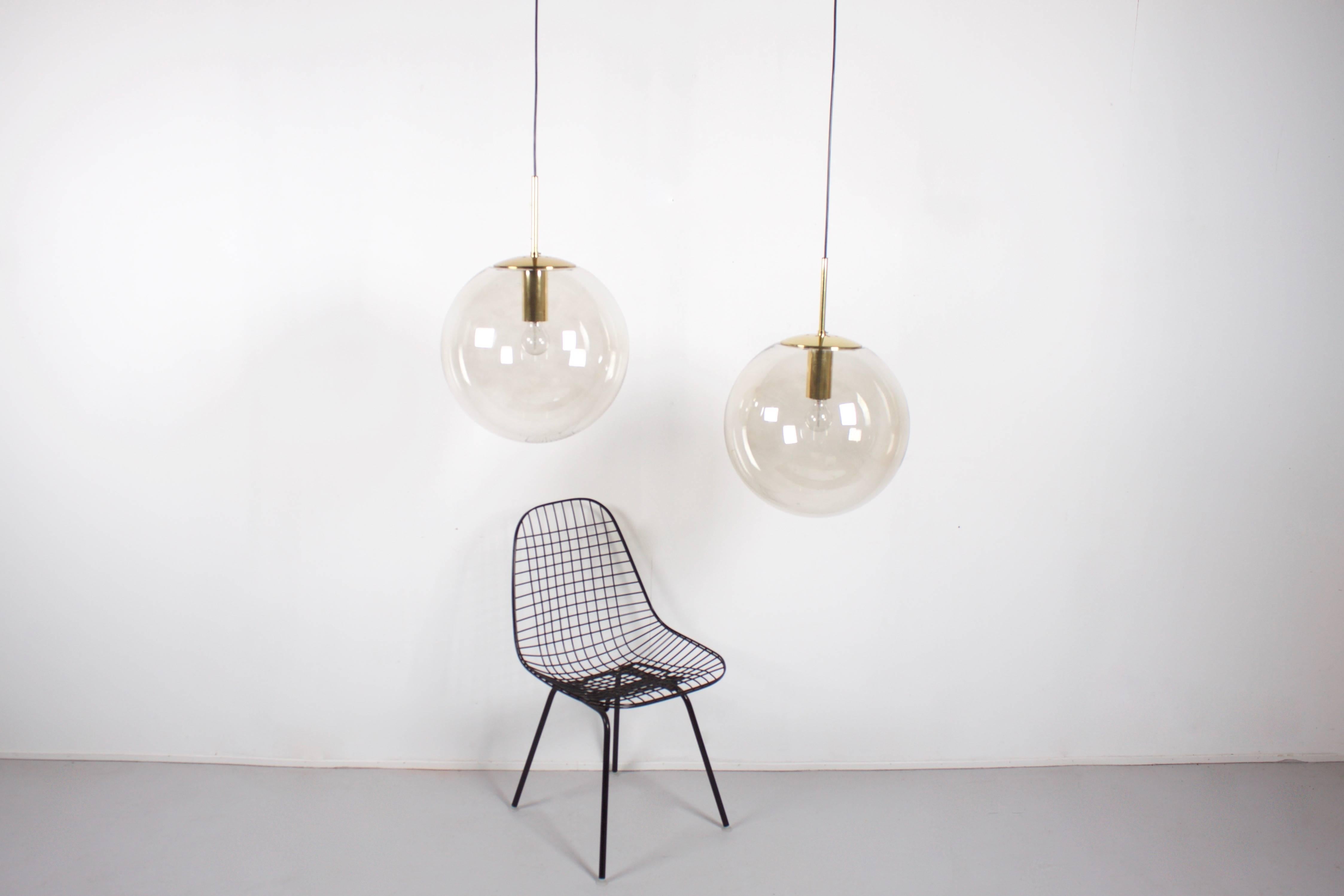 Large Glashütte Limburg pendants in beautiful condition. 

Brass hardware. 

Handblown clear glass globes which give a warm light effect, 40 cm. in diameter 

Black cord and canopy. 

The length of the cord can be customized for free.