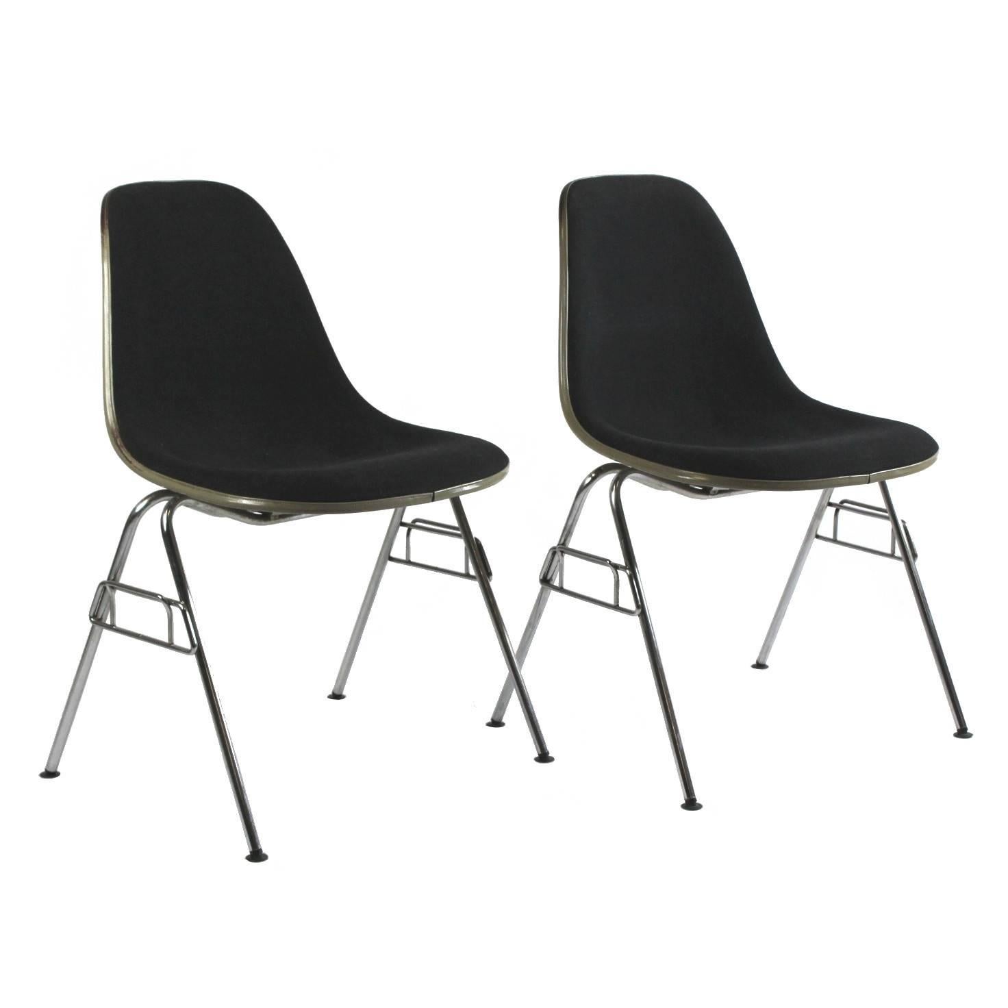 Stacking chairs designed by Ray and Charles Eames in 1955 and manufactured by Herman Miller in the U.S. fiberglass seat shells, dark blue upholstery. Both of the chairs are labeled Herman Miller under the seat.