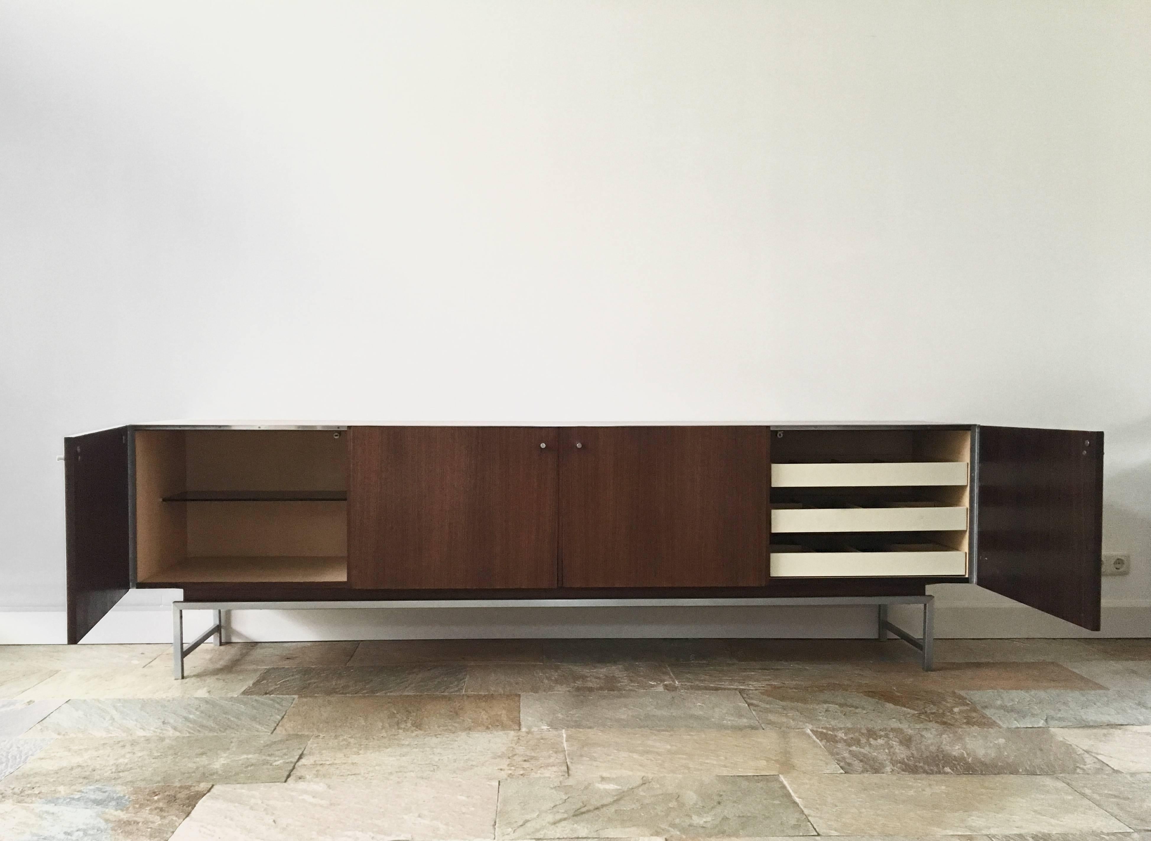 This sideboard (VDJ-245) was manufactured by Fristho Franeker in The Netherlands in the 1960s. It was designed by Kurt Gunther and Horst Brechtmann in 1961. This dresser is made from Indian palissander / Rosewood with a metal frame, and It also