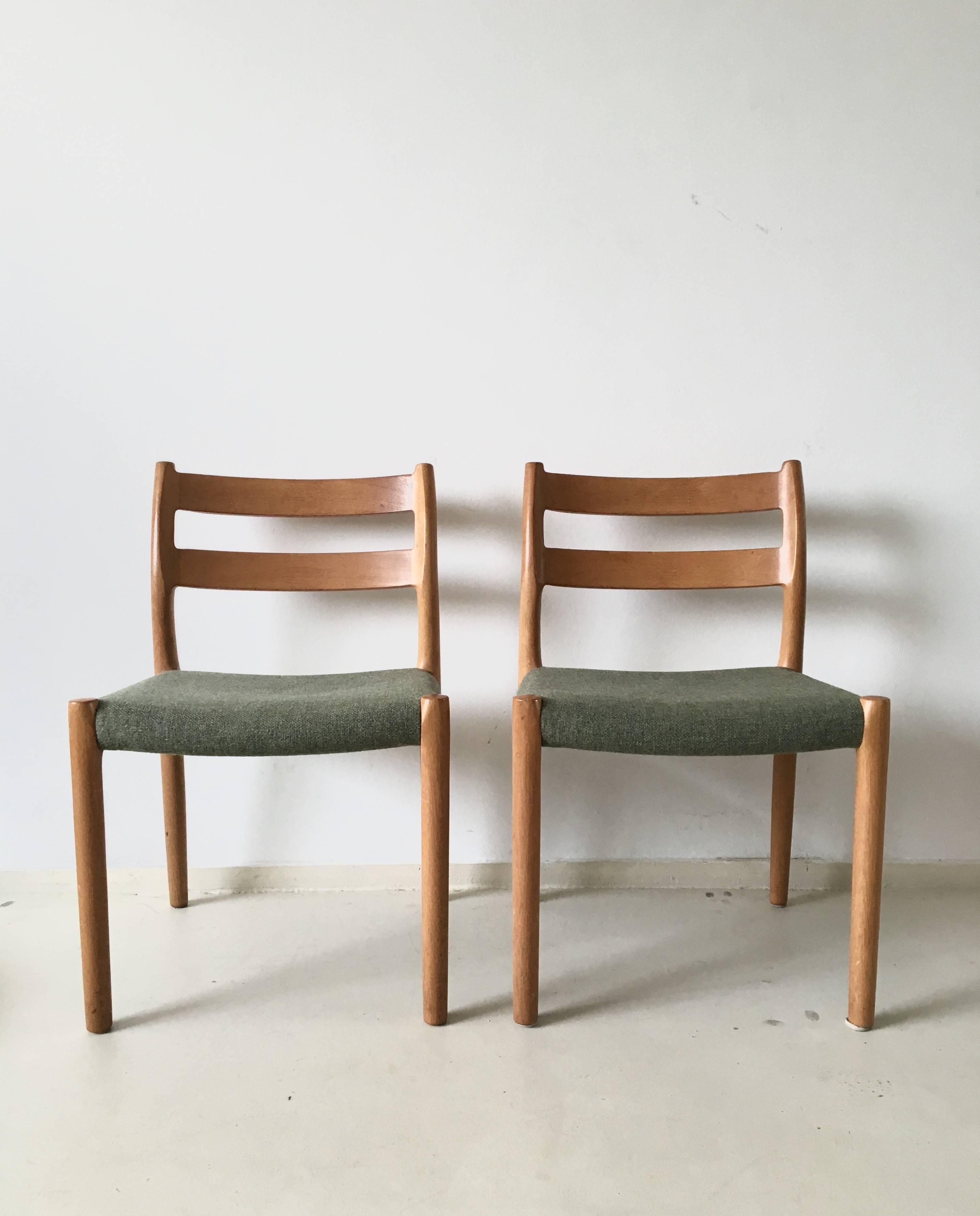 Set of two dining chairs designed by J.L. Moller and manufactured by Højbjerg Denmark, circa 1960s. The chairs have elegant curved frames in massive teak, and upholstery in green colored wool.

They remain in excellent condition.