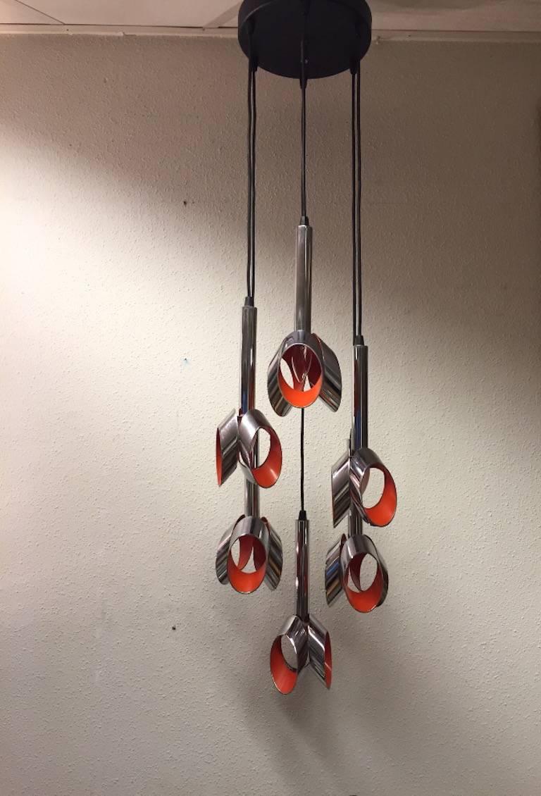 This wonderful modernist lamp consists of six chromed pendants which are originally laquered orange on the inside. Each pendant can be adjusted in height. The ceiling plate diameter is approximately 33 cm.

The length of the whole lamp with the