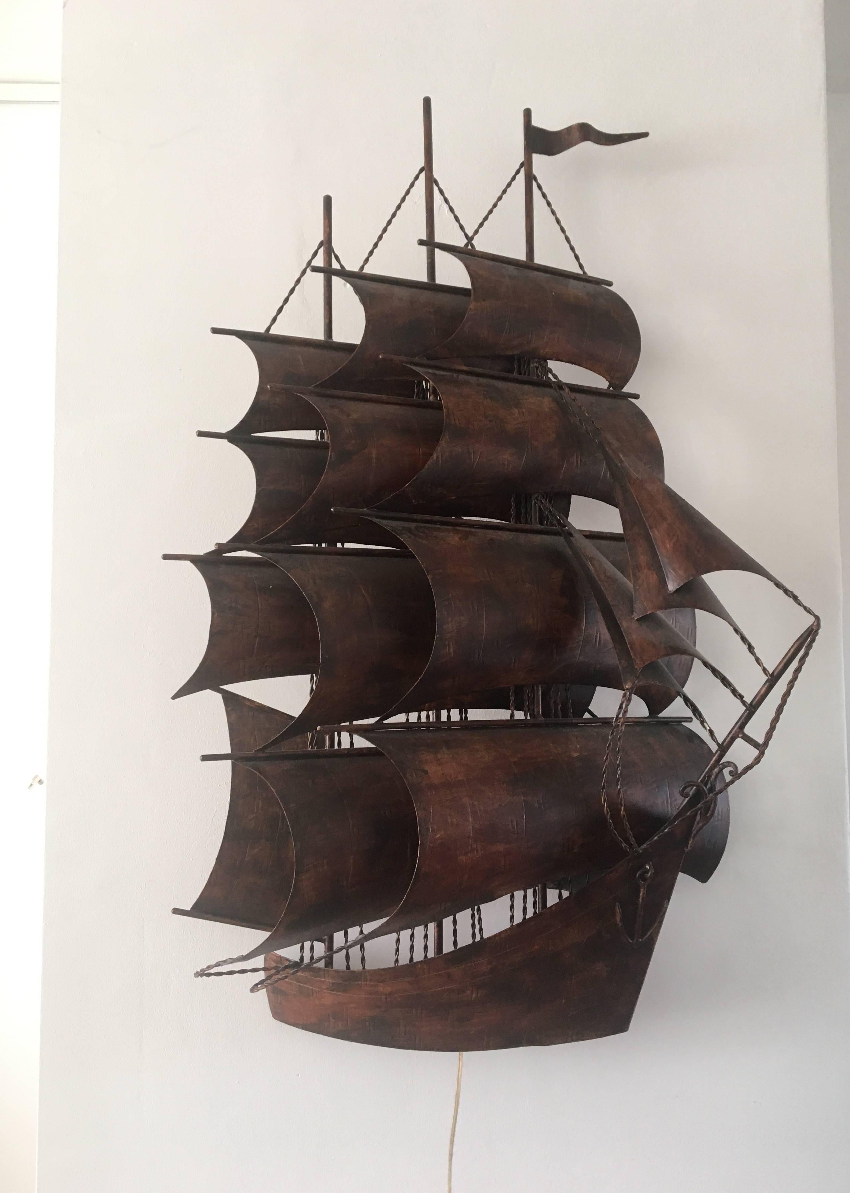 This large metal boat was manufactured, circa the 1960s. It was designed three dimensional, so it looks as if the boat comes right out of the wall. 

This sculpture has lights (6 bulbs) at the back to give it a beautifull extra dimension. The