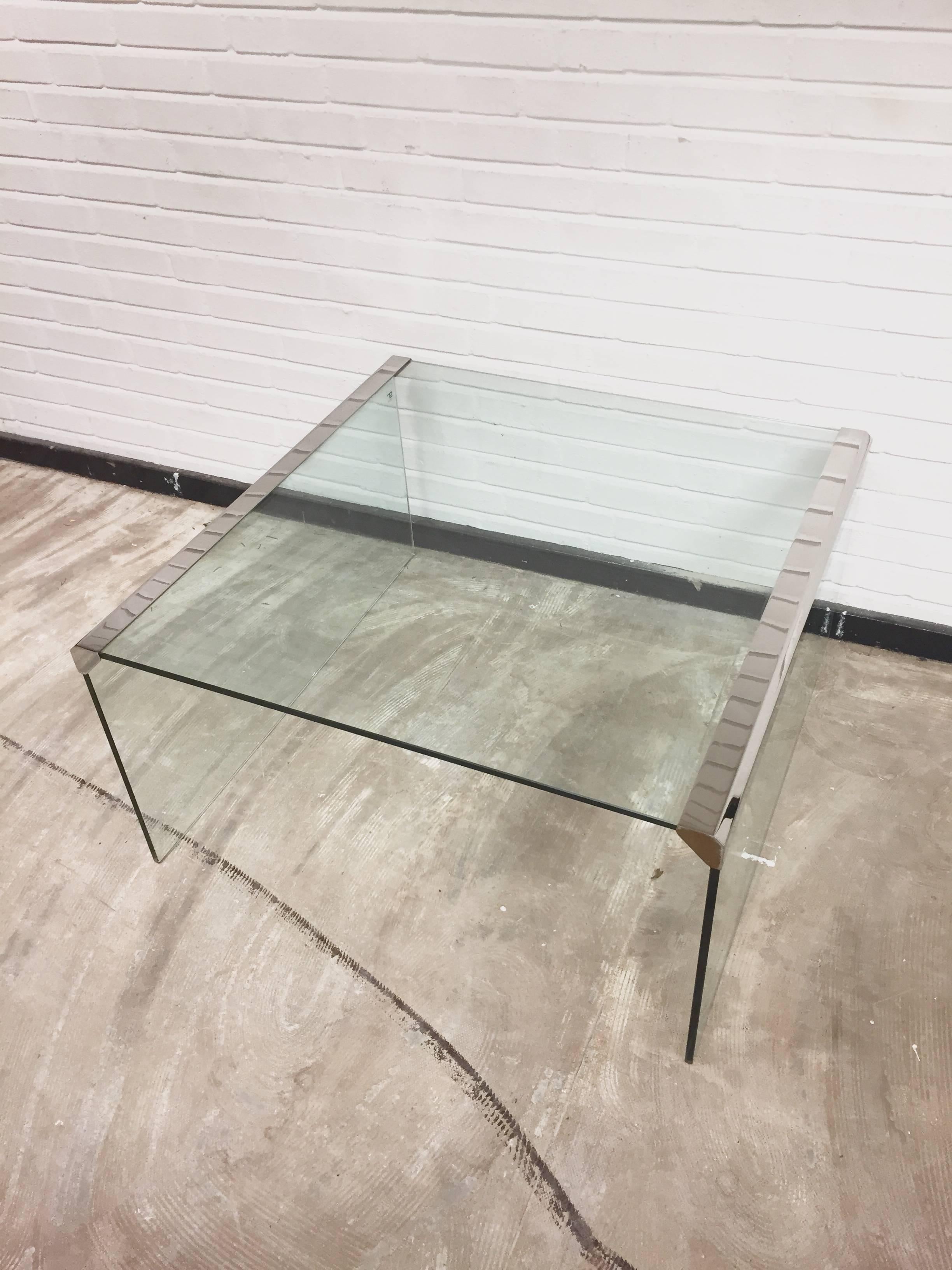 This coffee table, model T33, was designed by Pierangelo Gallotti for his company, Gallotti & Radice in 1982. It features a thick tempered transparent glass top with stainless steel edges. The table is in a good vintage condition with a few signs of