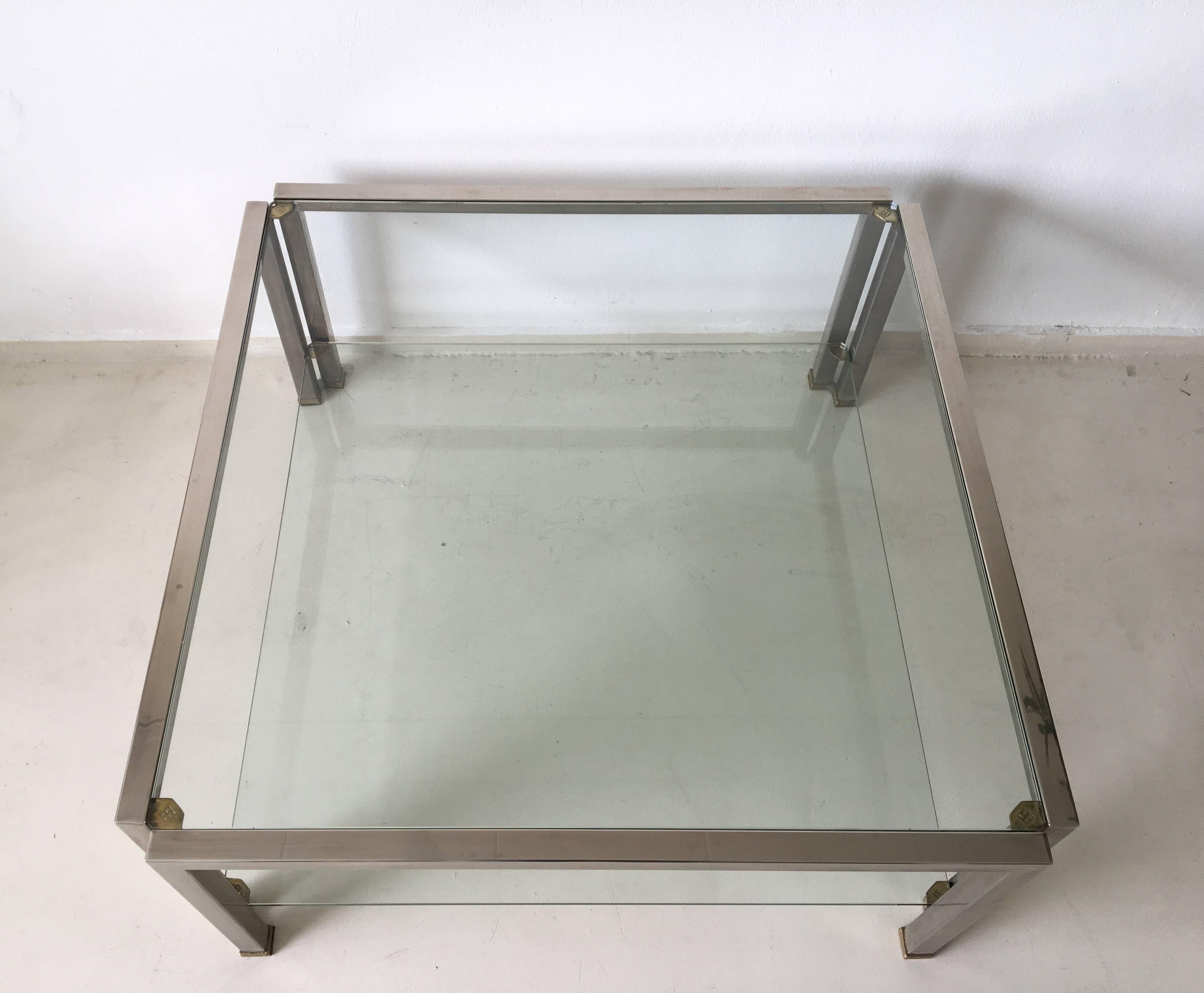 This glass coffee table with two shelves, was designed and manufactured by Peter Ghyczy in the Netherlands in 1986. It's frame is fabricated in 3x3 cm stainless steel square tubing fastened together with with brass and ribbed fittings. The glass top