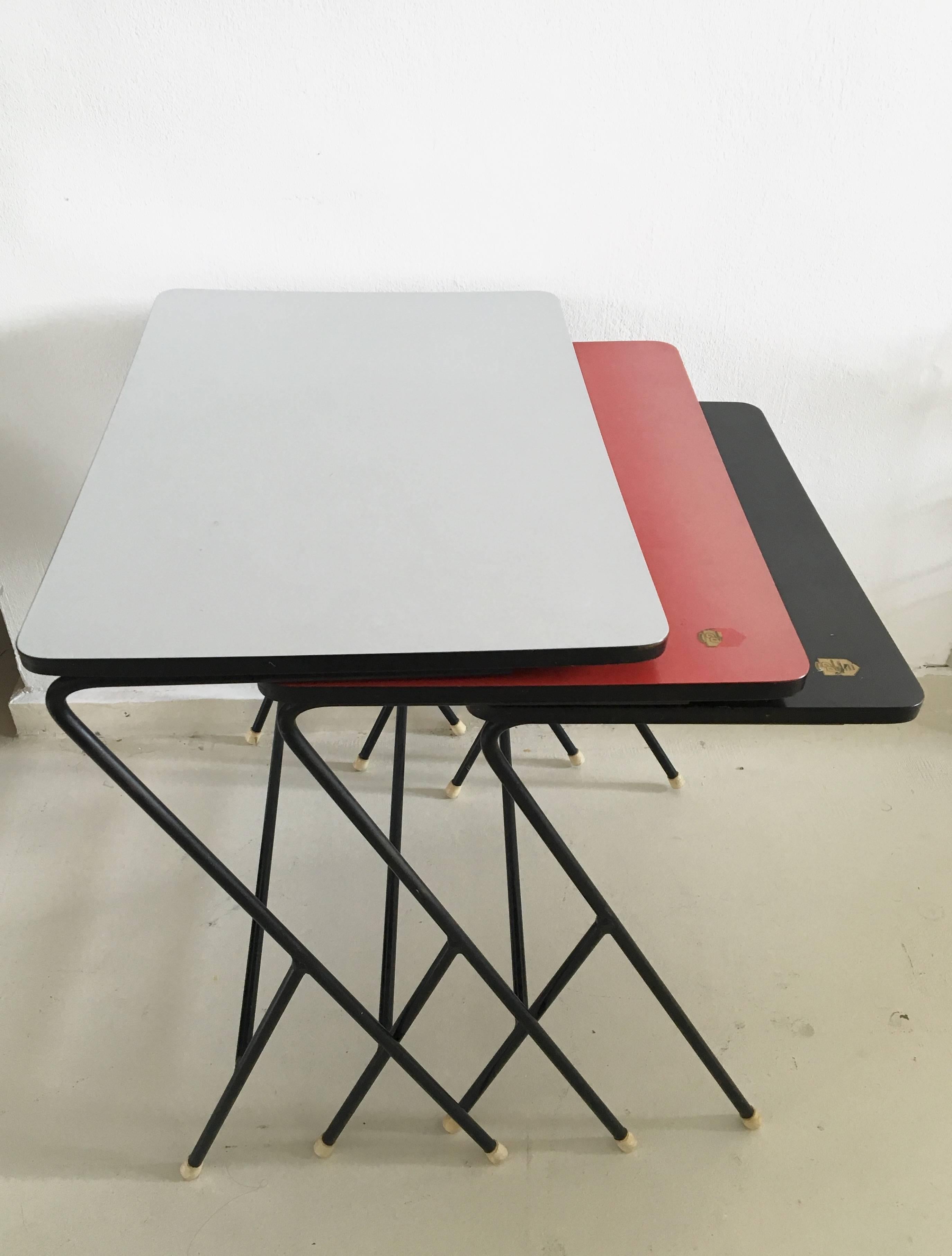 This set of three features a metal frame with Y legs and a Perstorp panel in three colors, which was made in Sweden. (Grey, red and black).

The tables remain in a very good condition with minor signs of age and use. The red table has some