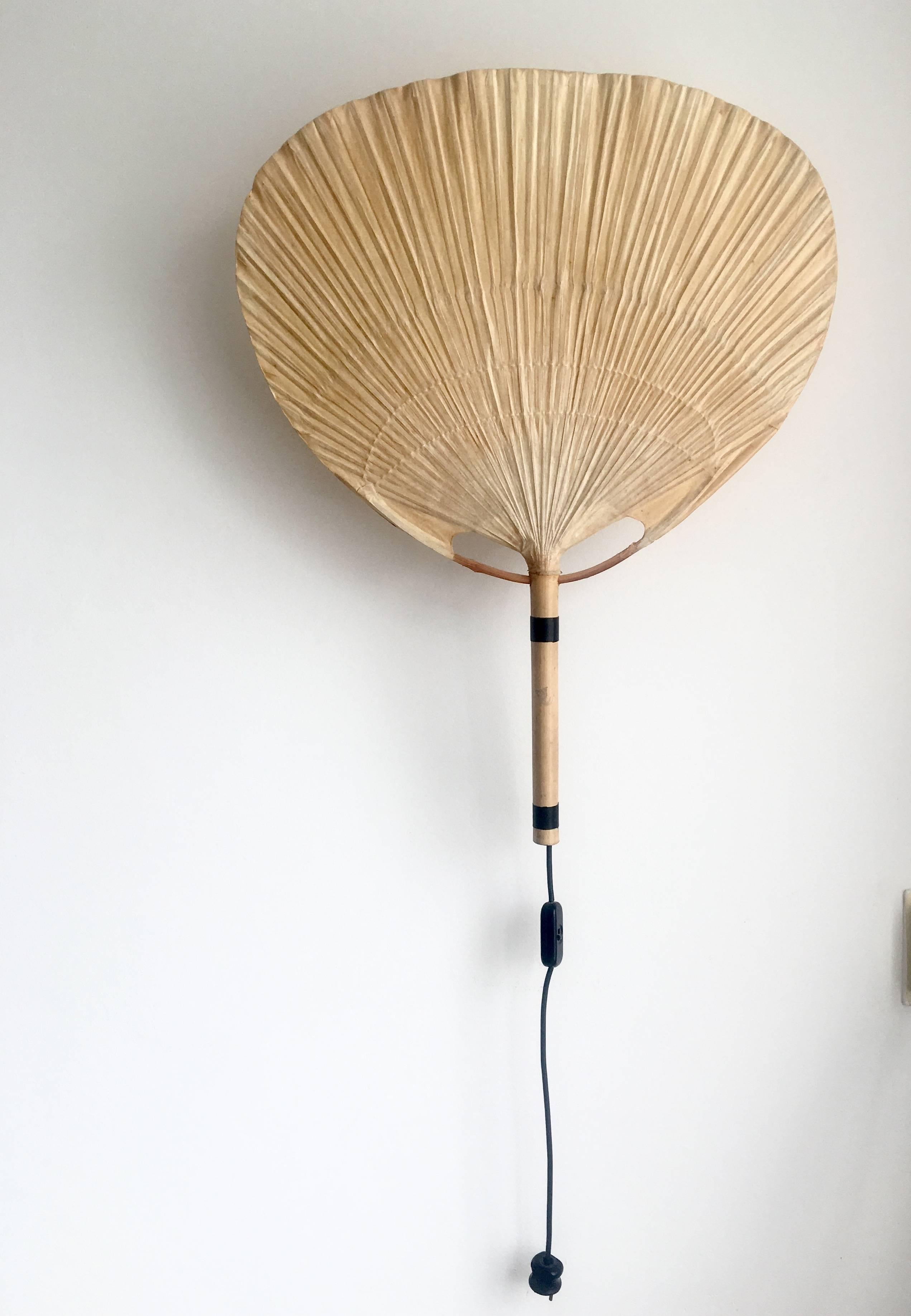 The Uchiwa lamp was designed by Ingo Maurer, in Germany, 1973. From the start, Maurer's interest in paper for lampshades was linked with his interest in Japan. 

The lamp gives an amazing warm light when lit. It's made from bamboo with a rice