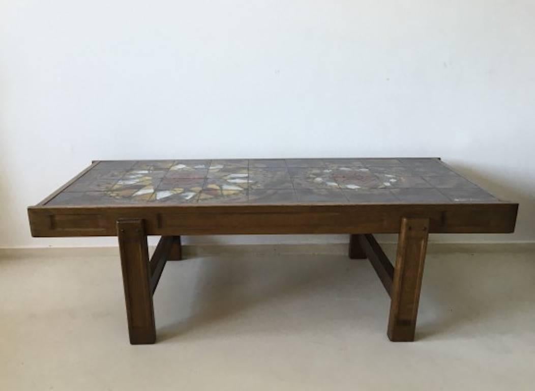 This coffee table was designed and manufactured in Belgium by J. Belarti during the 1970s. 

The frame is made of solid dark stained oak and holds a signed Belarti ceramic composition of multi colored 'floral designs. Belarti was a famous Belgian