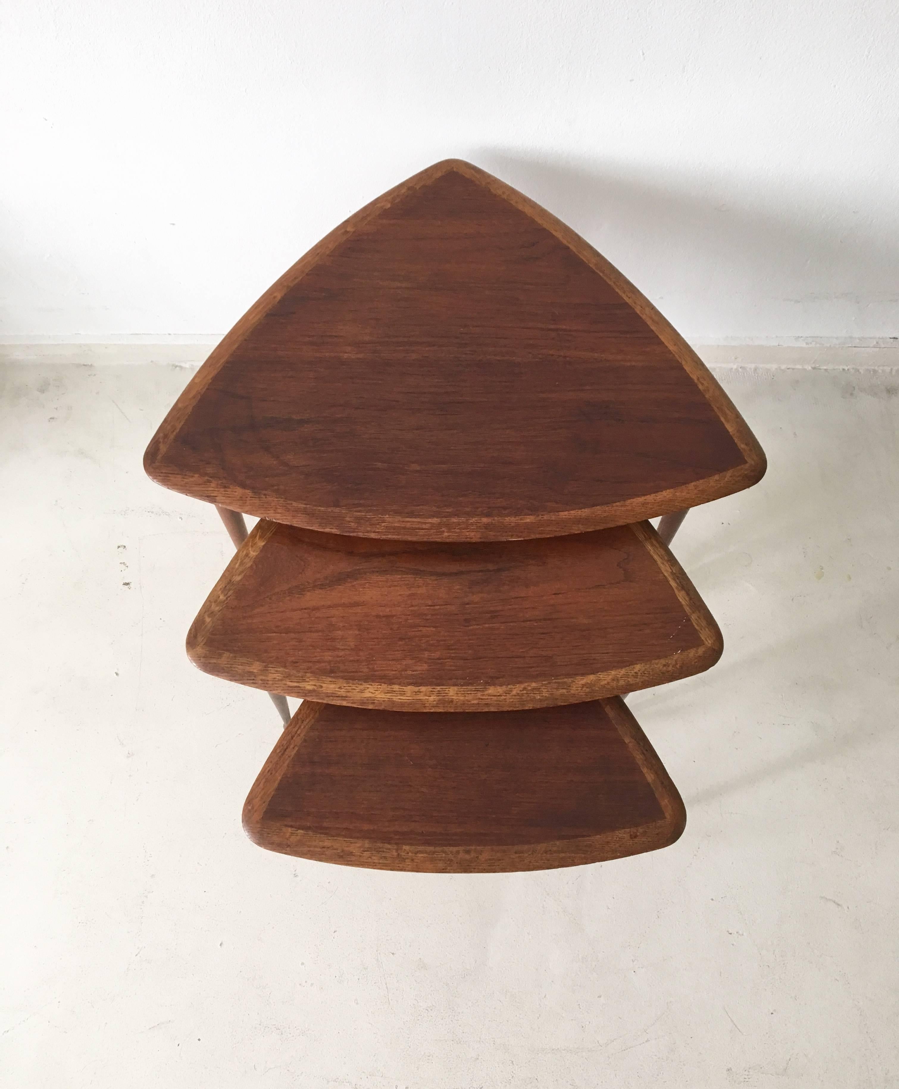 This wonderful set consists of three tables manufactured in teakwood. They feature tapered drumstick legs. The set remains in good solid condition, with some wear to the table tops.