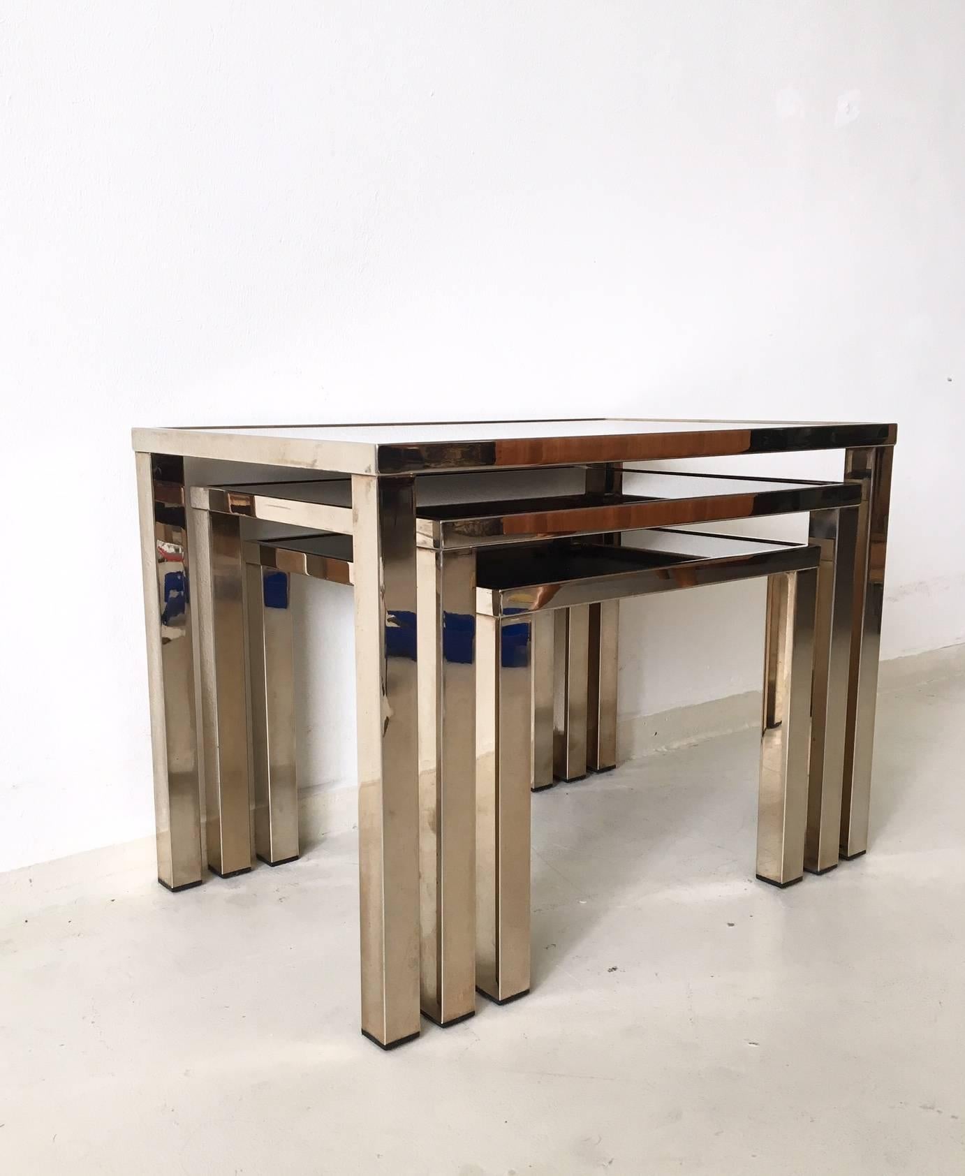 This rare set of three nesting tables were manufactured in Belgium, circa 1960s-1970s. They feature a gold-plated metal frame and mirrored glass. One table has a small spot of corrosion or chip in the glass and another one, a very small chip (see