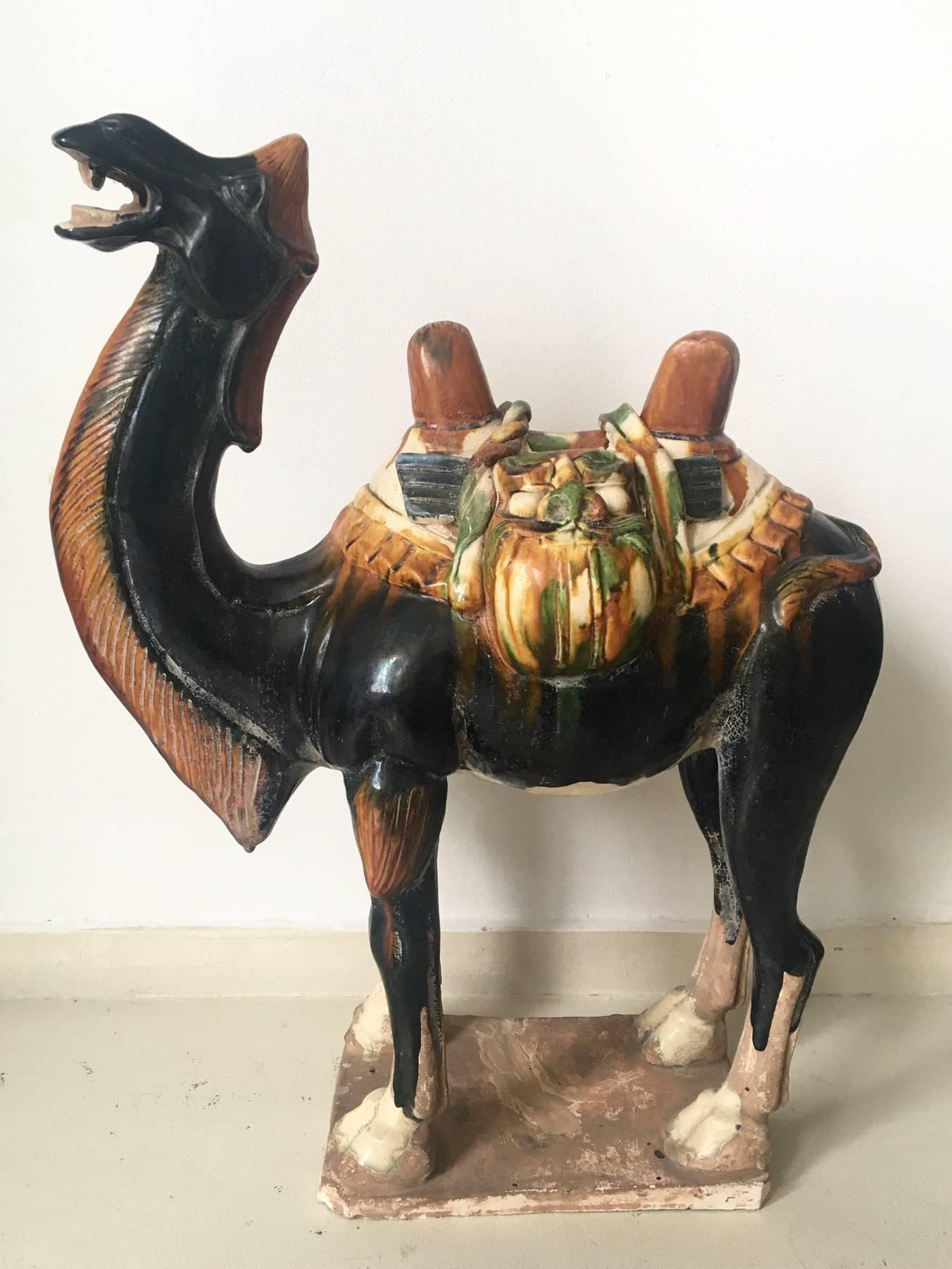 This absolute stunning positioned camel was manufactured in China, circa 1960s and finished with a Sancai glaze. It's saddlebags show a man's face. Free shipping to Continental Europe and Continental US!

