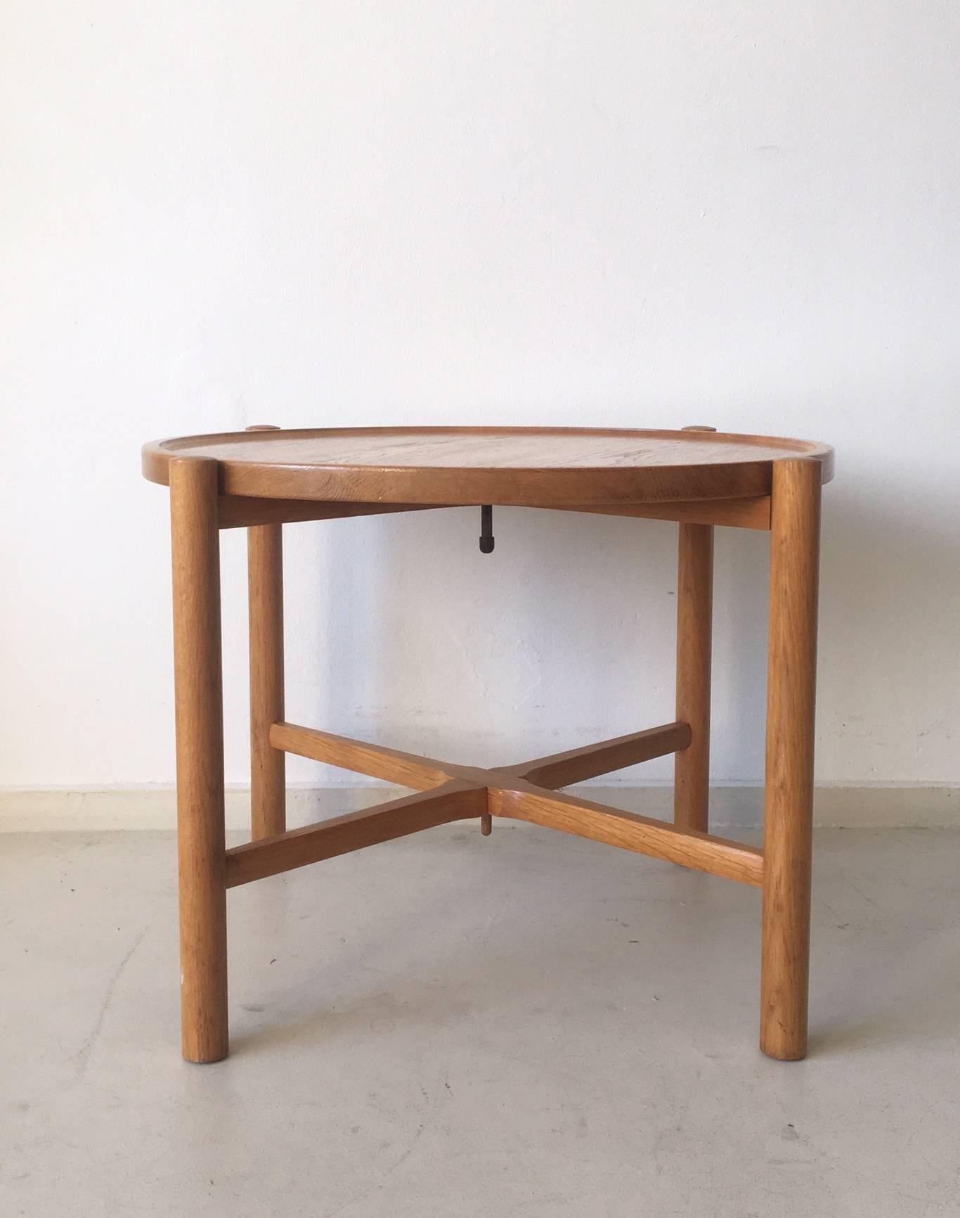 This foldable table was designed by Hans Wegner in 1945 for Andreas Tuck. In 1973 the production was taken over by PP Mobler. It's moest wooden tray is unattached, so could be reversed or replaced. Also an Additional Tray can be placed on the lower