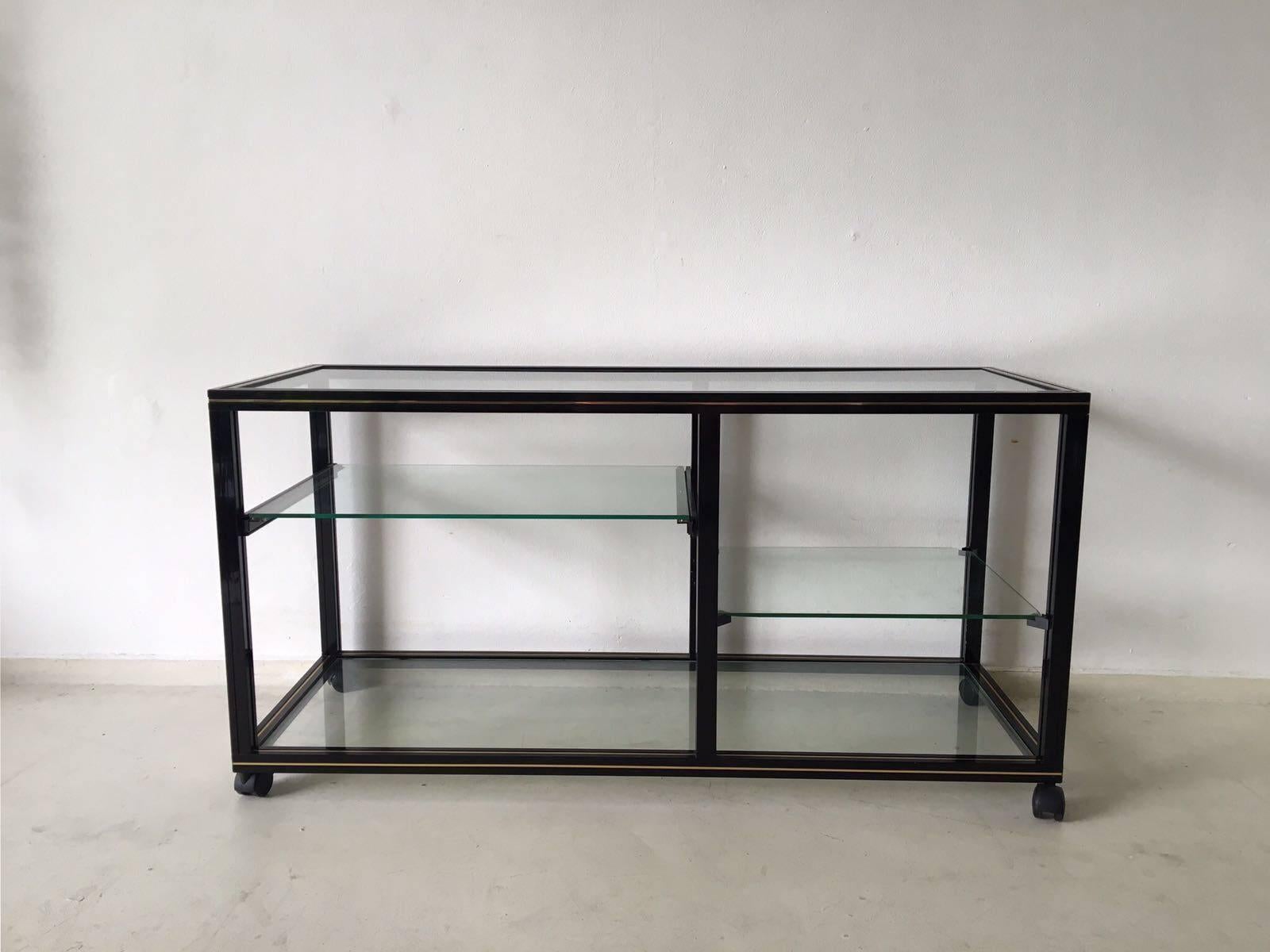 Beautiful contemporary TV/side-table designed by Pierre Vandel during the 1970s, Paris, France. This table features a black lacquered metal frame with brass trims, wheels and an extendable glass sheet. 

It remains in a good vintage condition,