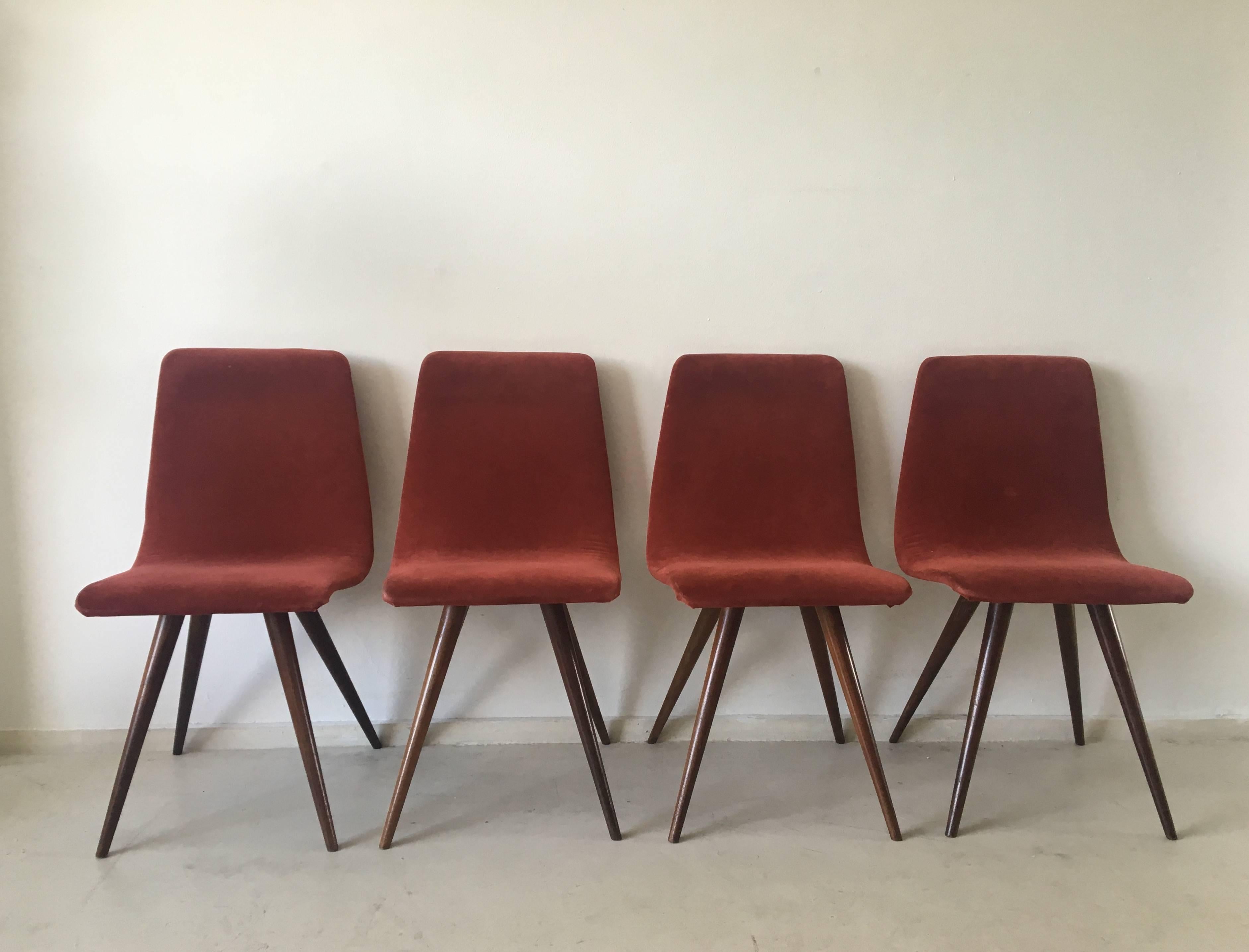 This set of four dining chairs were designed in The Netherlands by, most likely, G.J. Van Os circa the 1950s. The chairs feature a flexible seating with red/red brown fabric, we think they might have been reupholstered with it. Their unusual feet