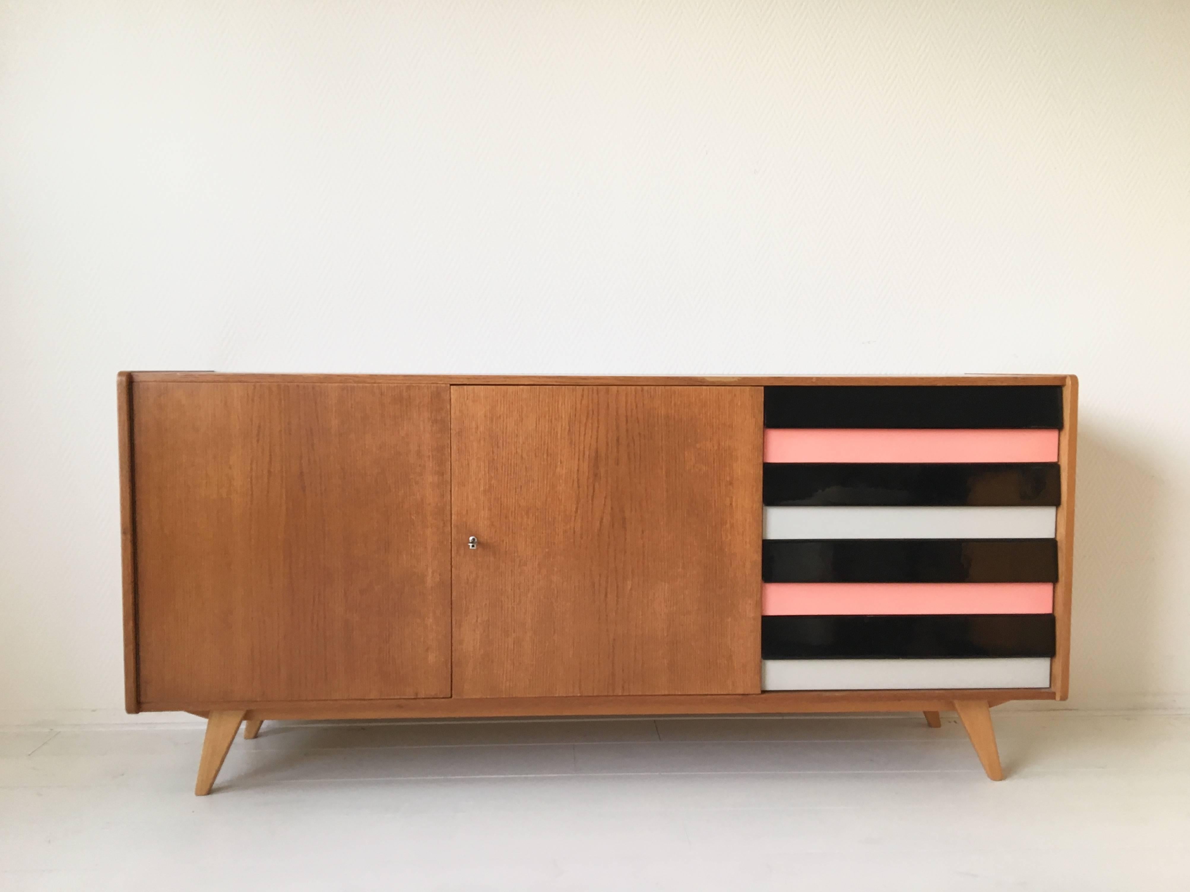 First shown at the Brussels expo in 1958, this elegant sideboard designed by Jiri Jiroutek for Interier Praha.
This piece features a teak veneered structure with two doors and four drawers in Pink, White and Black.
Good condition with wear